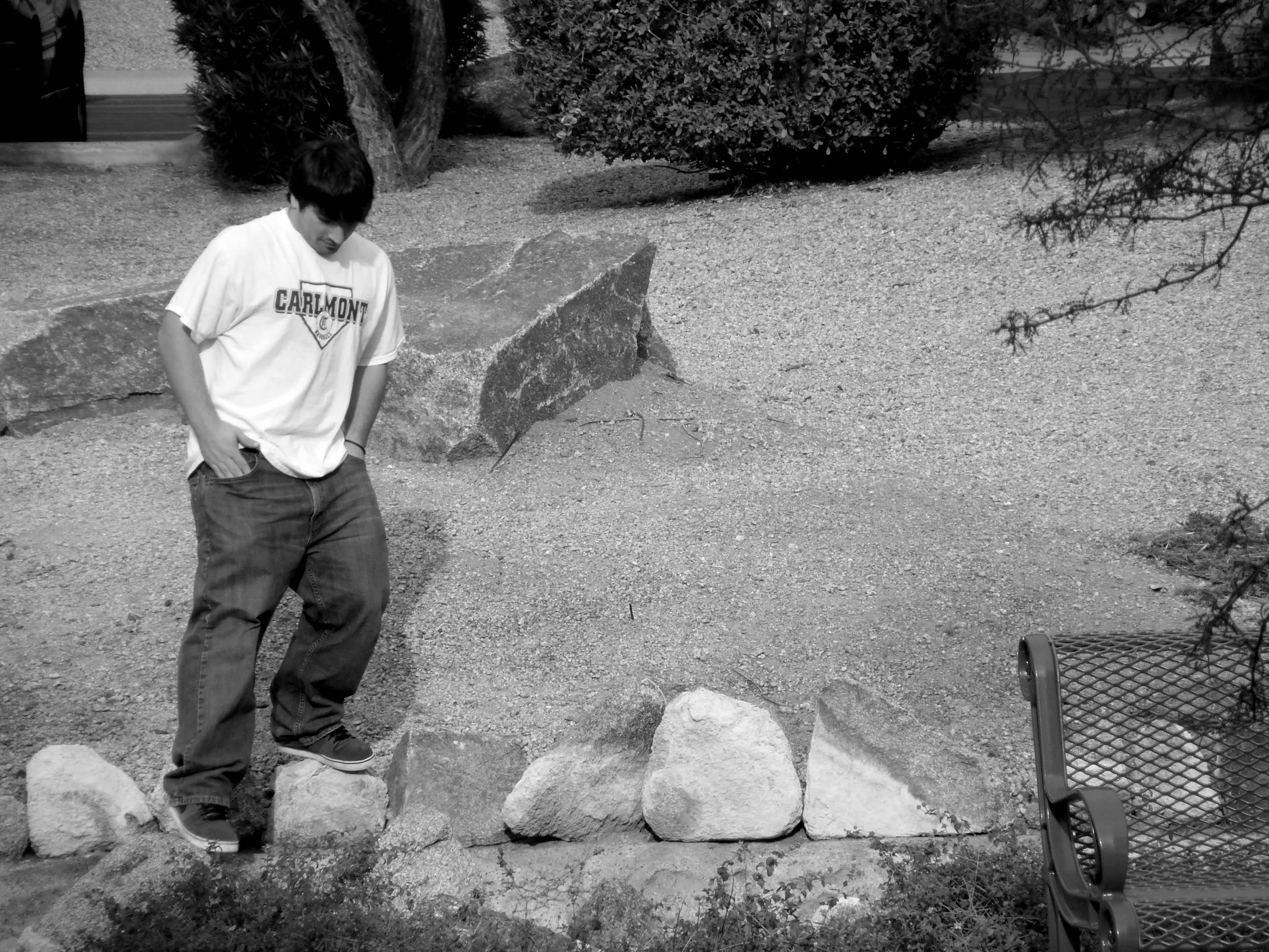 Black and white boy in Carlmont t-shirt standing on stones. 