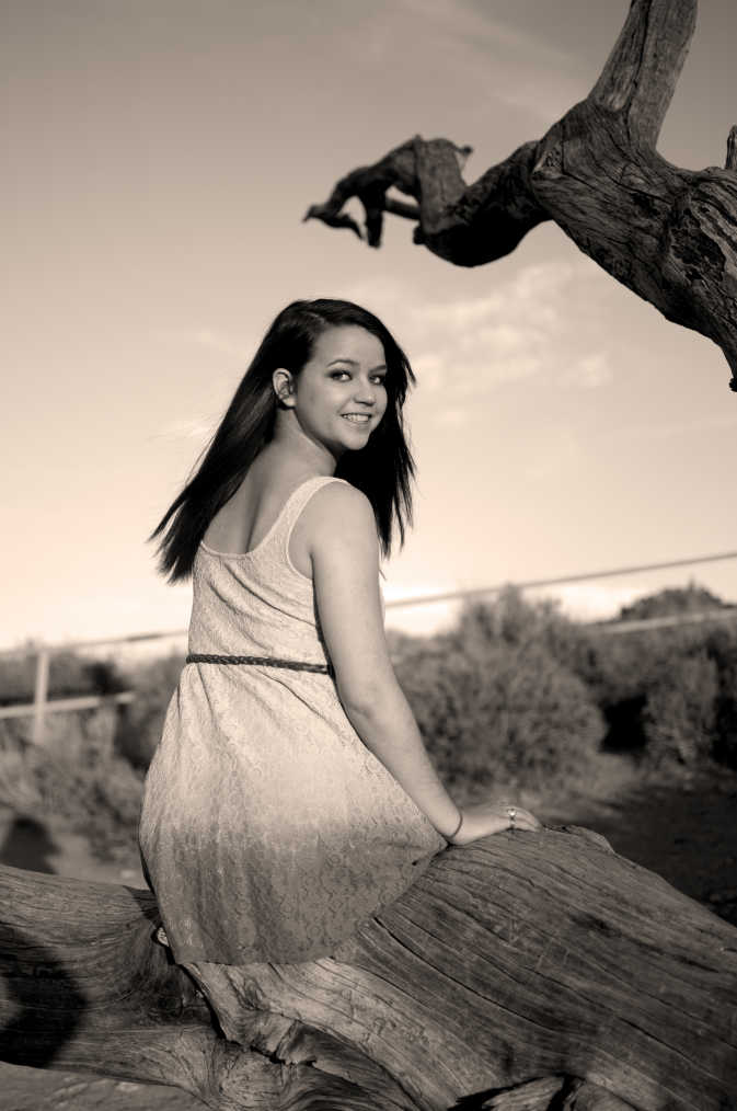 Black and white girl in the desert looking over her shoulder at the camera. 