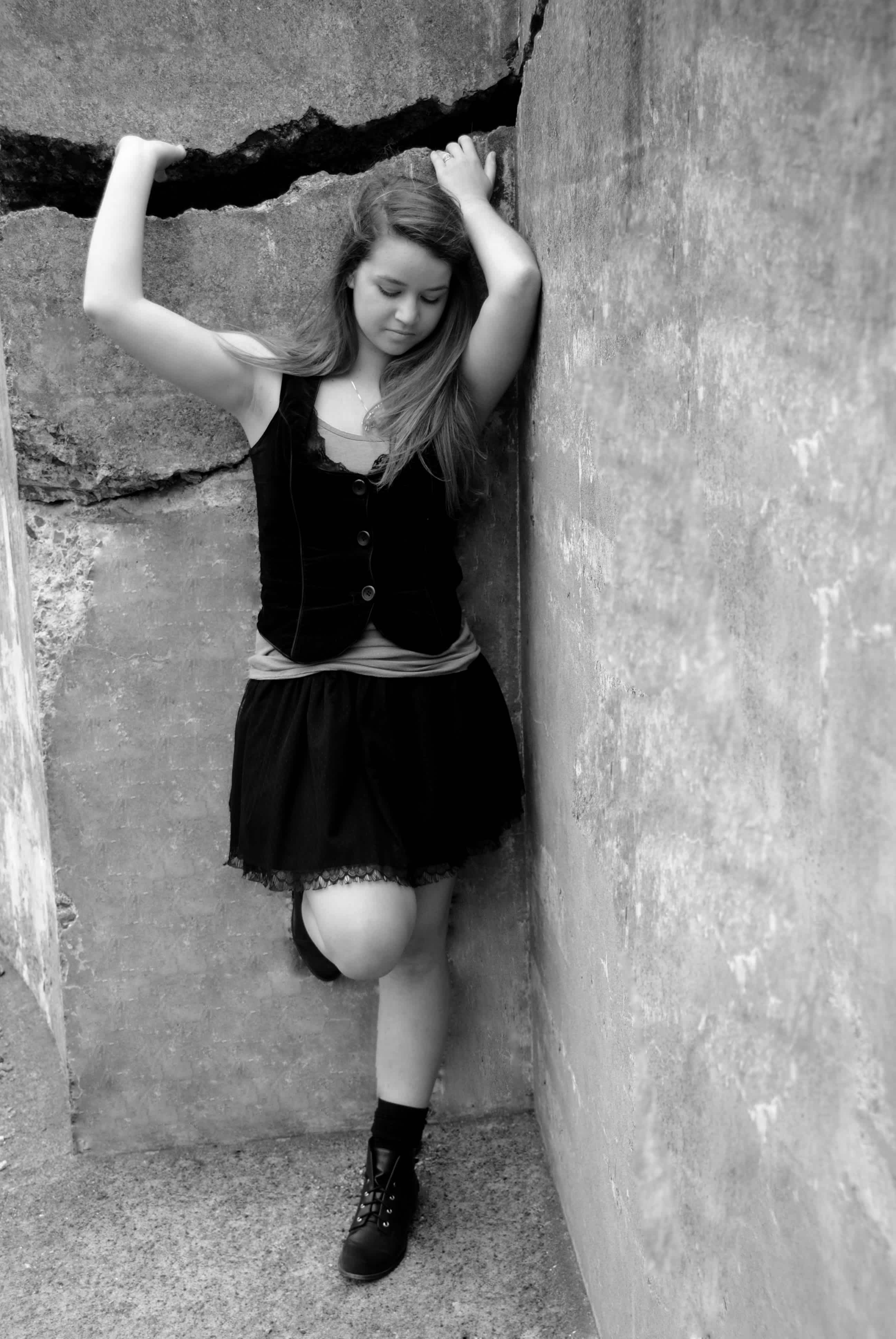 Girl leaning against a rock wall. 