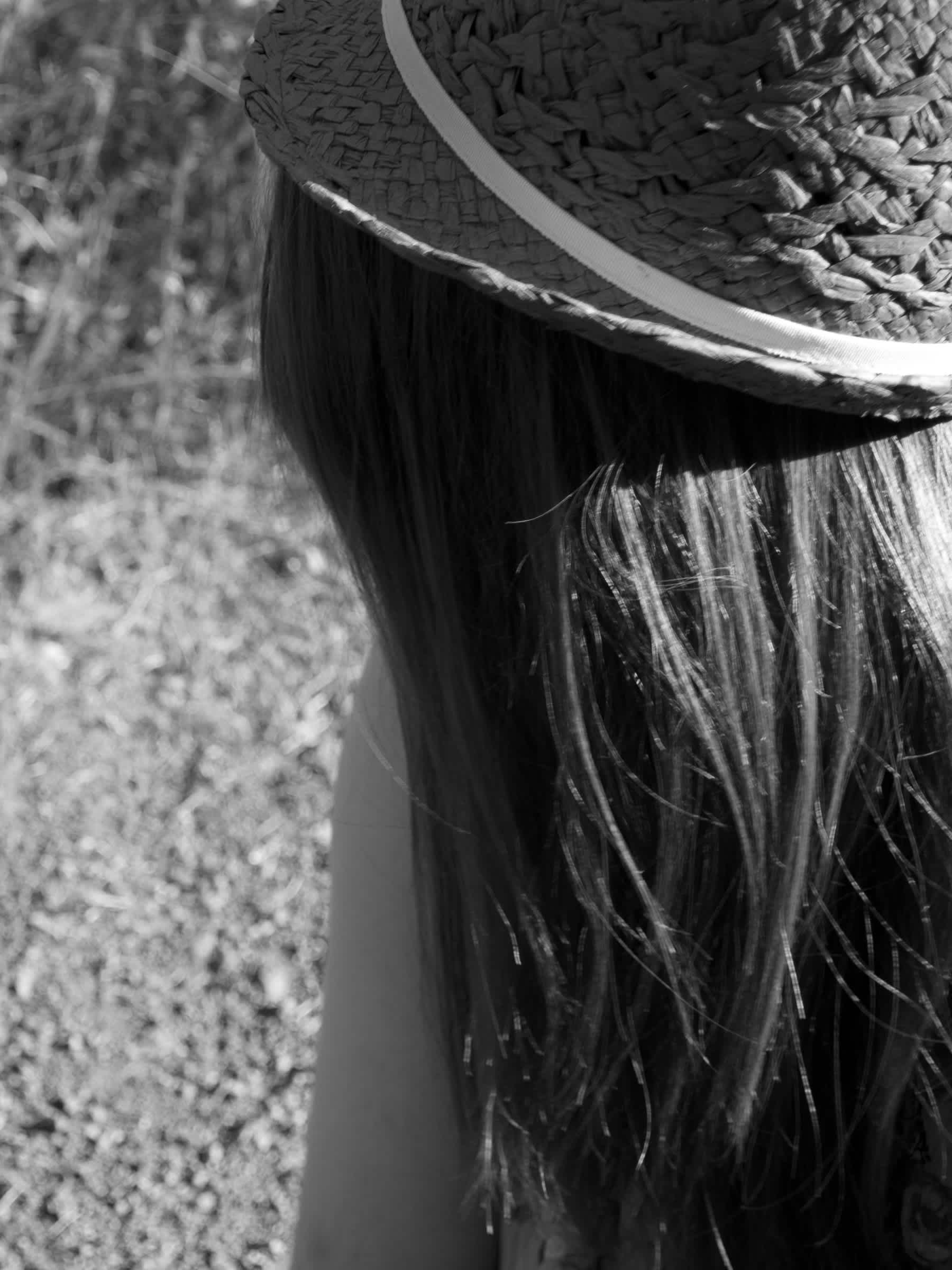 Black and white picture of the back of a girl wearing a hat's head. 