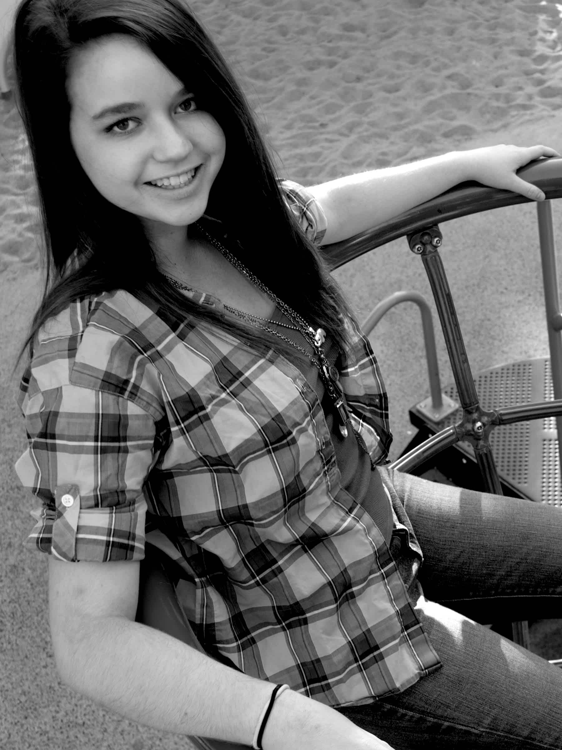 Black and white girl sitting against railing. 