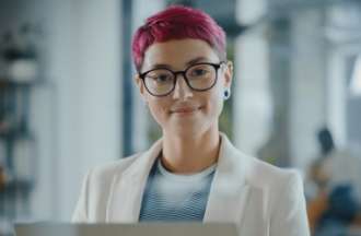 [Featured Image]:  A female, wearing a white jacket, glasses, and red hair. She is working at her desktop, performing her duties as a data scientist. 