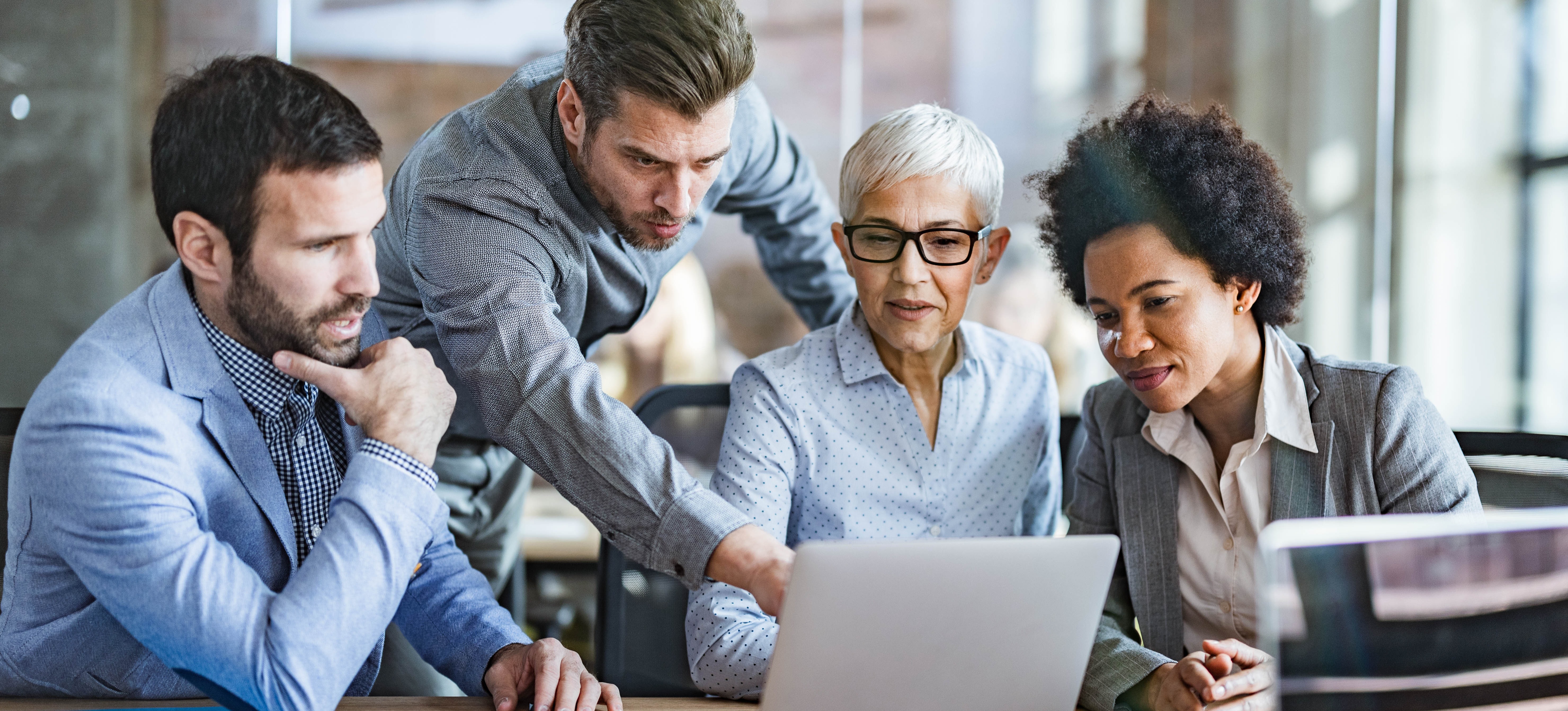 [Featured Image] A project team looks at a laptop as they use project management software to organize their project.