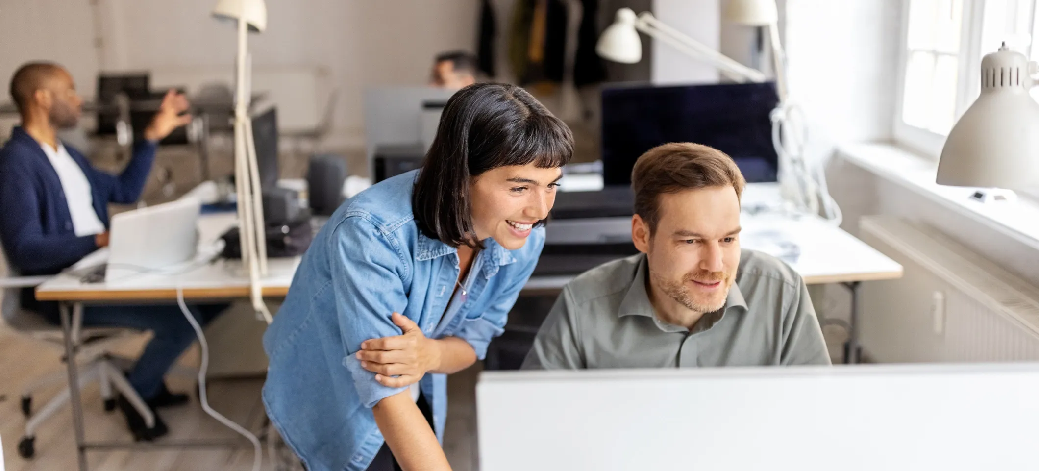 [Featured image] Two smiling developers look at a computer monitor in an office setting, working with Google ADK.
