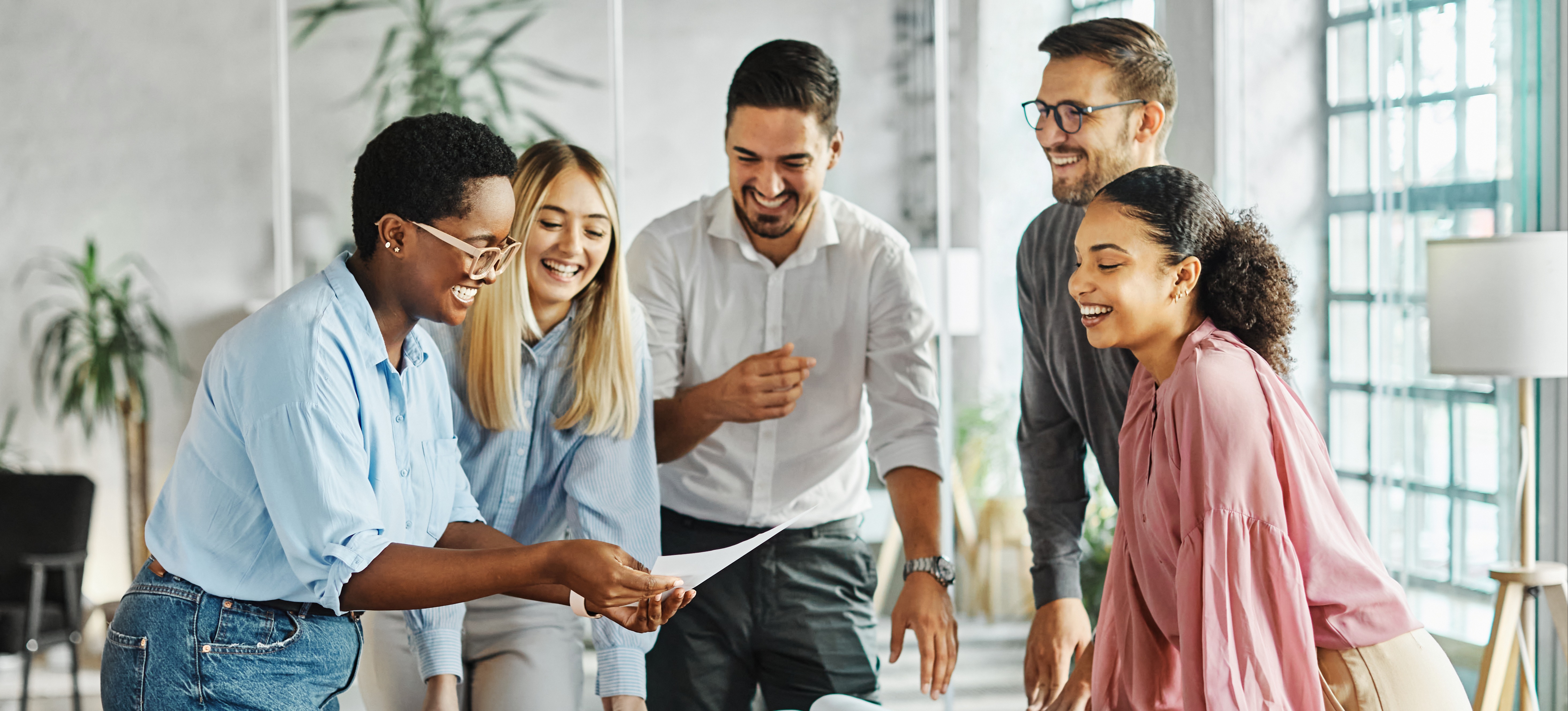 [Image en vedette] Un manager anime une discussion avec des collègues satisfaits, en utilisant le leadership transformationnel pour apporter des changements positifs.