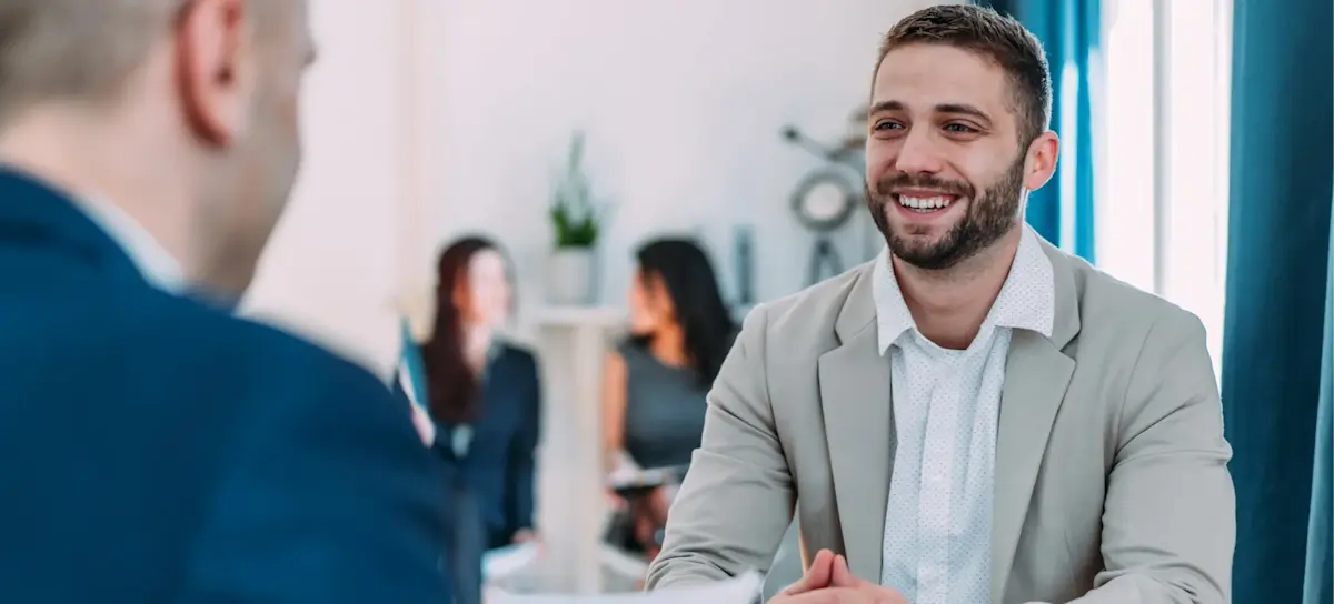 [Featured Image] A recruiter reviews a candidate's TensorFlow resume in a professional workplace while the candidate smiles during a discussion of their machine learning and artificial intelligence skills.