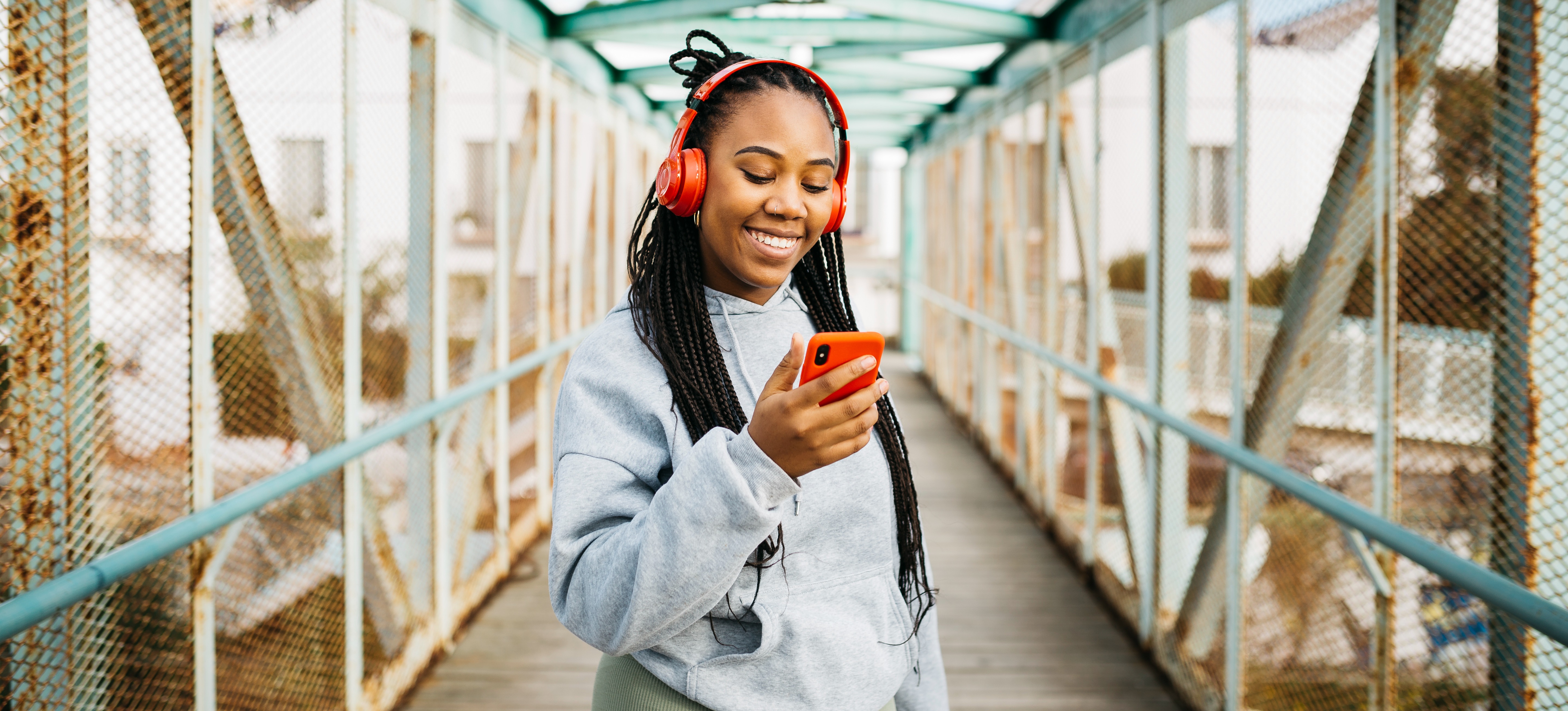 [Featured Image] A smiling runner on a bridge with headphones listens to a new song they discovered thanks to their music app’s agentic design pattern.
