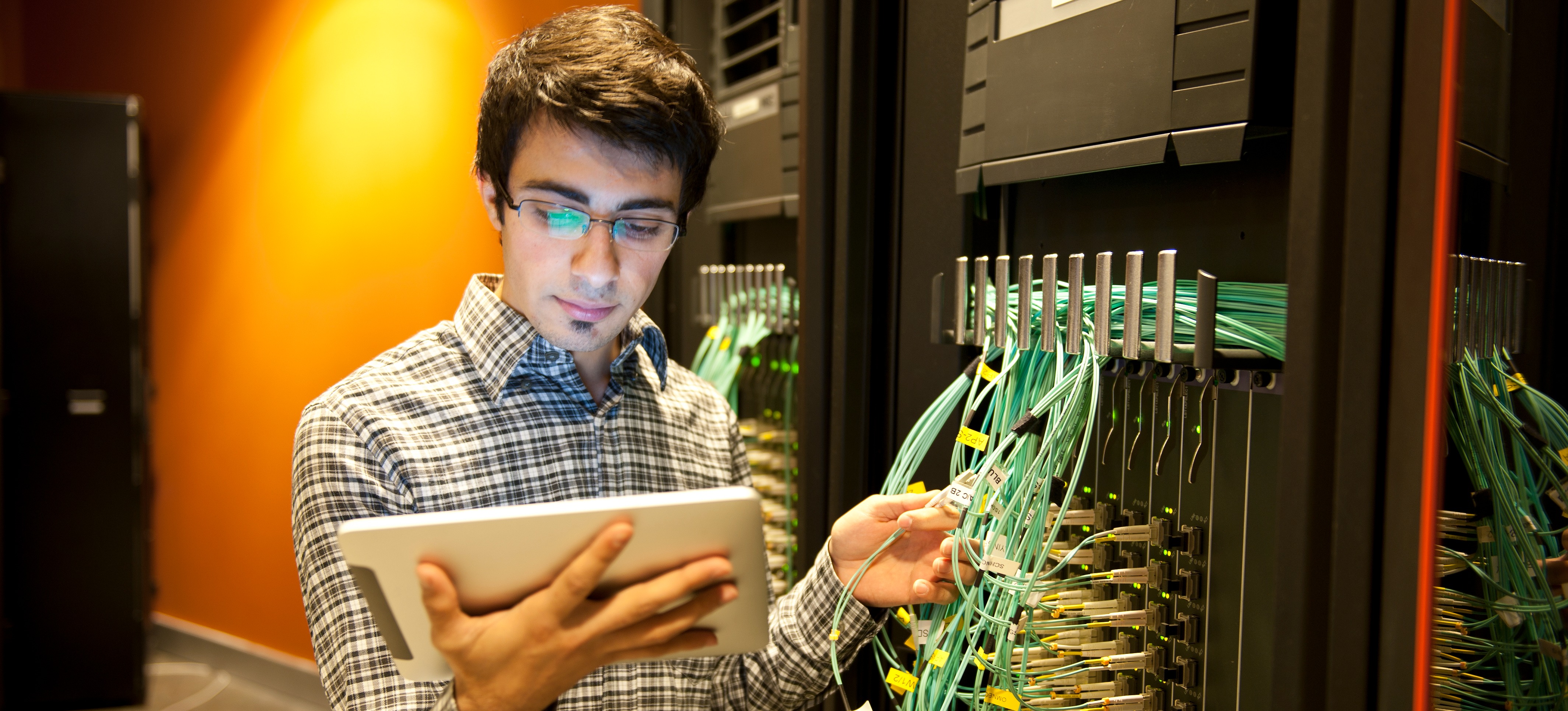 [Featured Image] A network administrator oversees both hardware and software in a server room.

