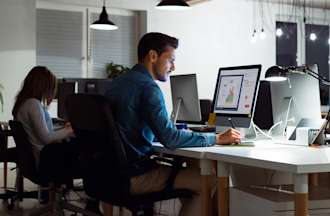 [Featured Image]:  A male wearing a blue shirt is sitting in front of his desktop, performing his duties as a data analyst. 