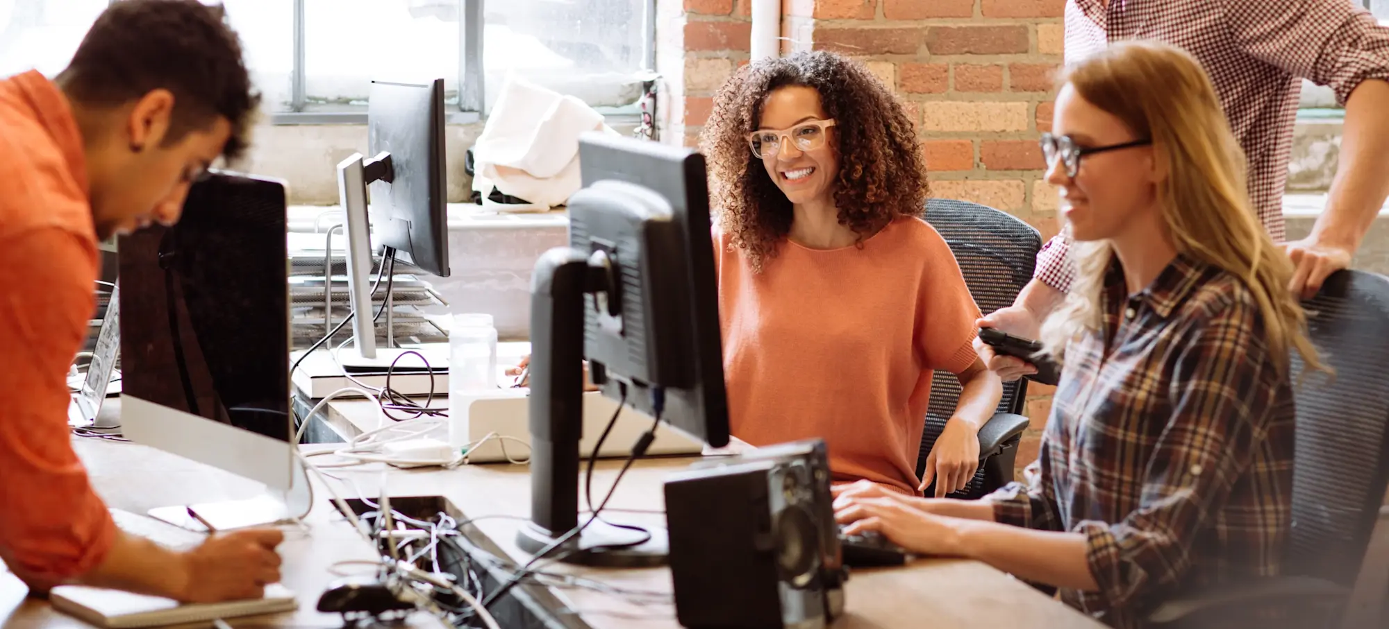 [Featured Image] An AR developer sits in a workspace, collaborating with a software development team.