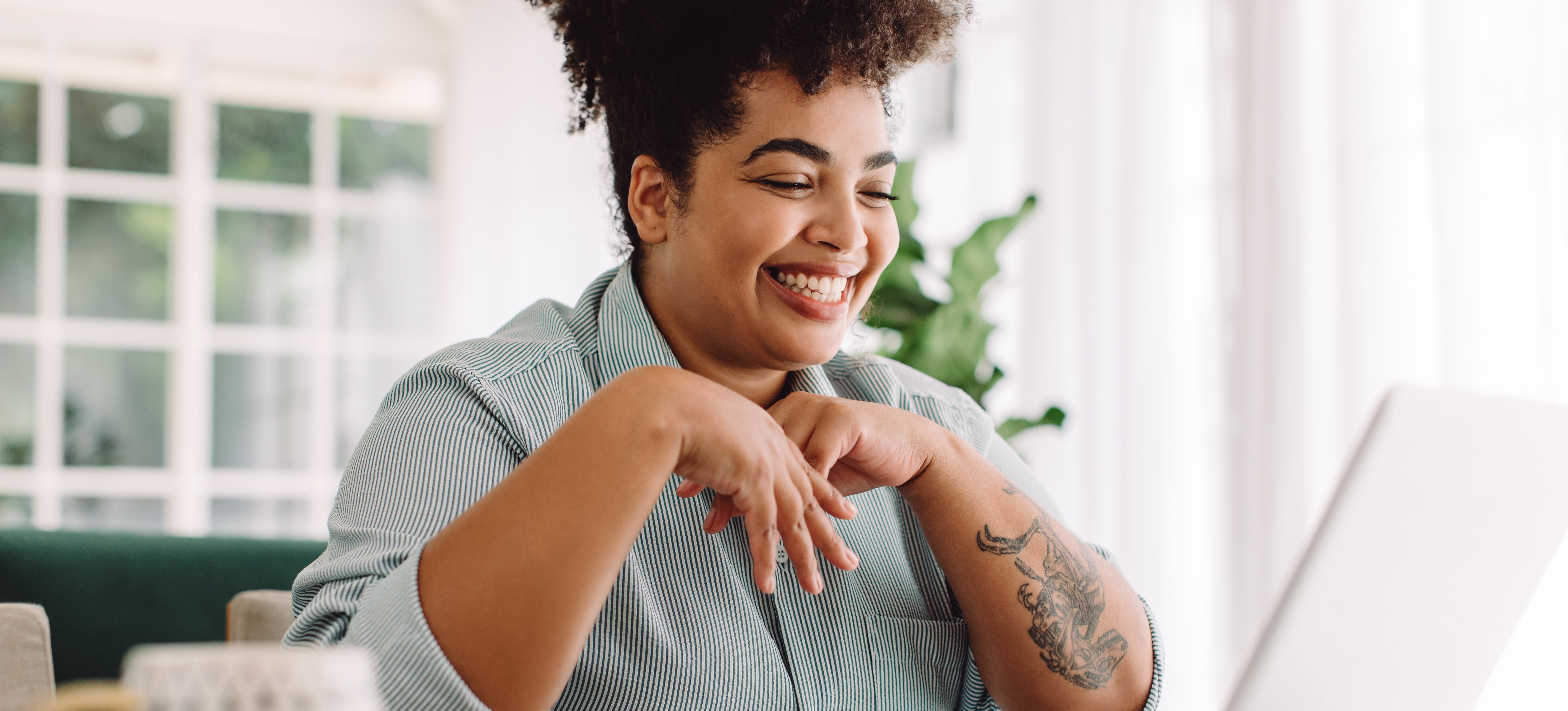 [Featured Image] A graphic designer sits in her home office and uses a laptop to review some visual concepts she completed. 