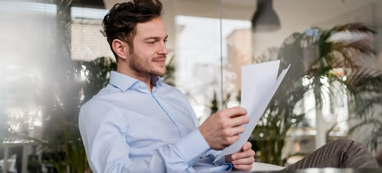 [Featured image] A person in a light blue button-up shirt examines their cover letter.