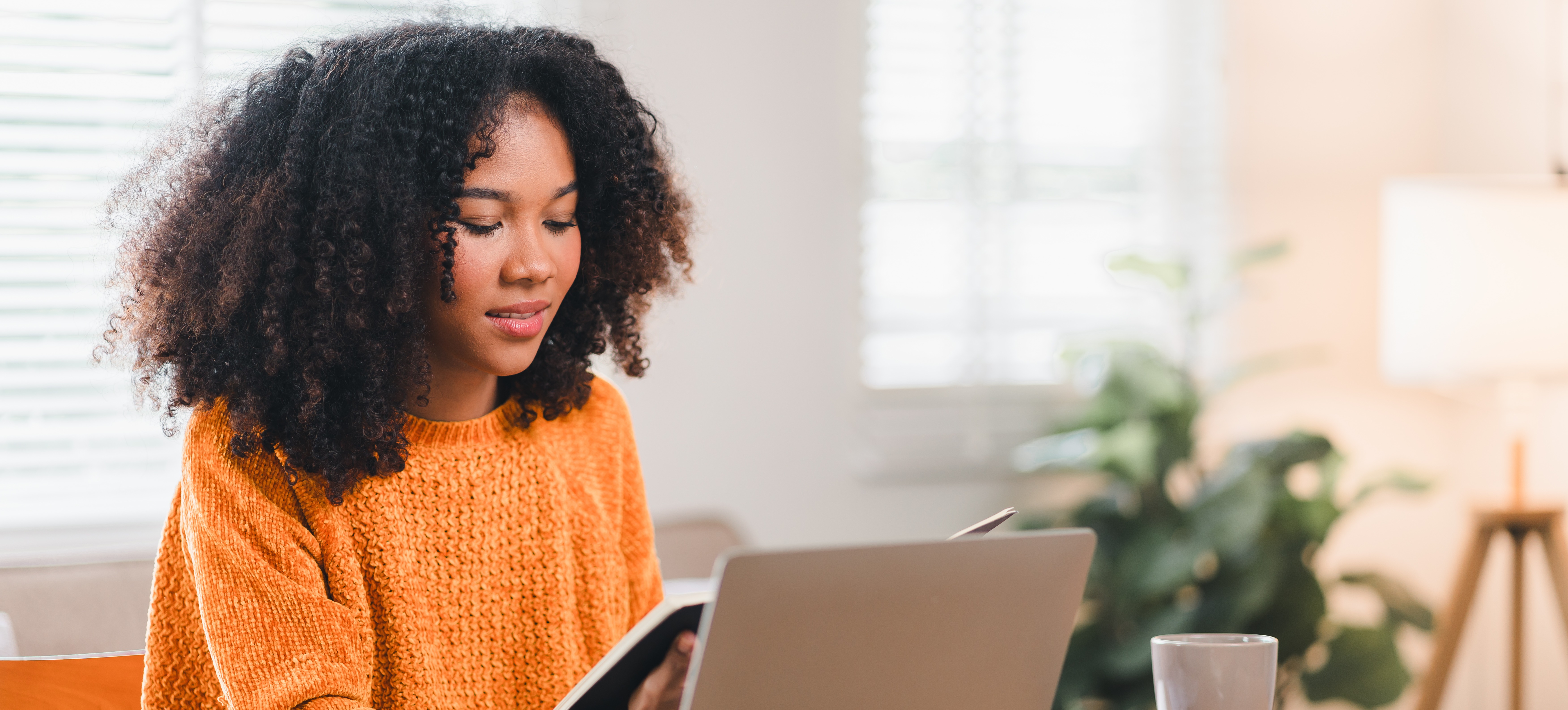 [Featured Image] A college student sits at a desk surrounded by various study materials.
