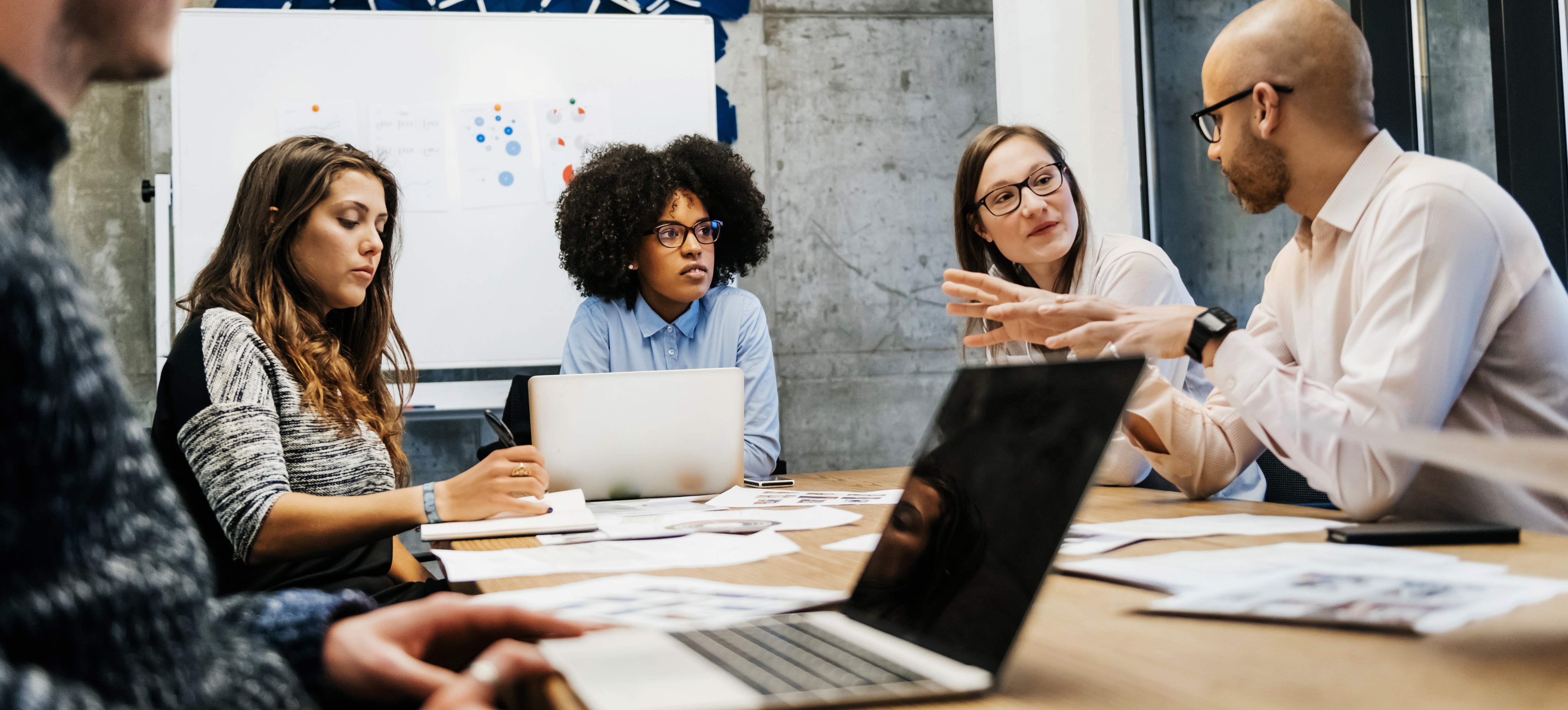 [Featured Image] A team of coworkers sits around a table in an office setting and engages in decision-making based on business intelligence systems.
