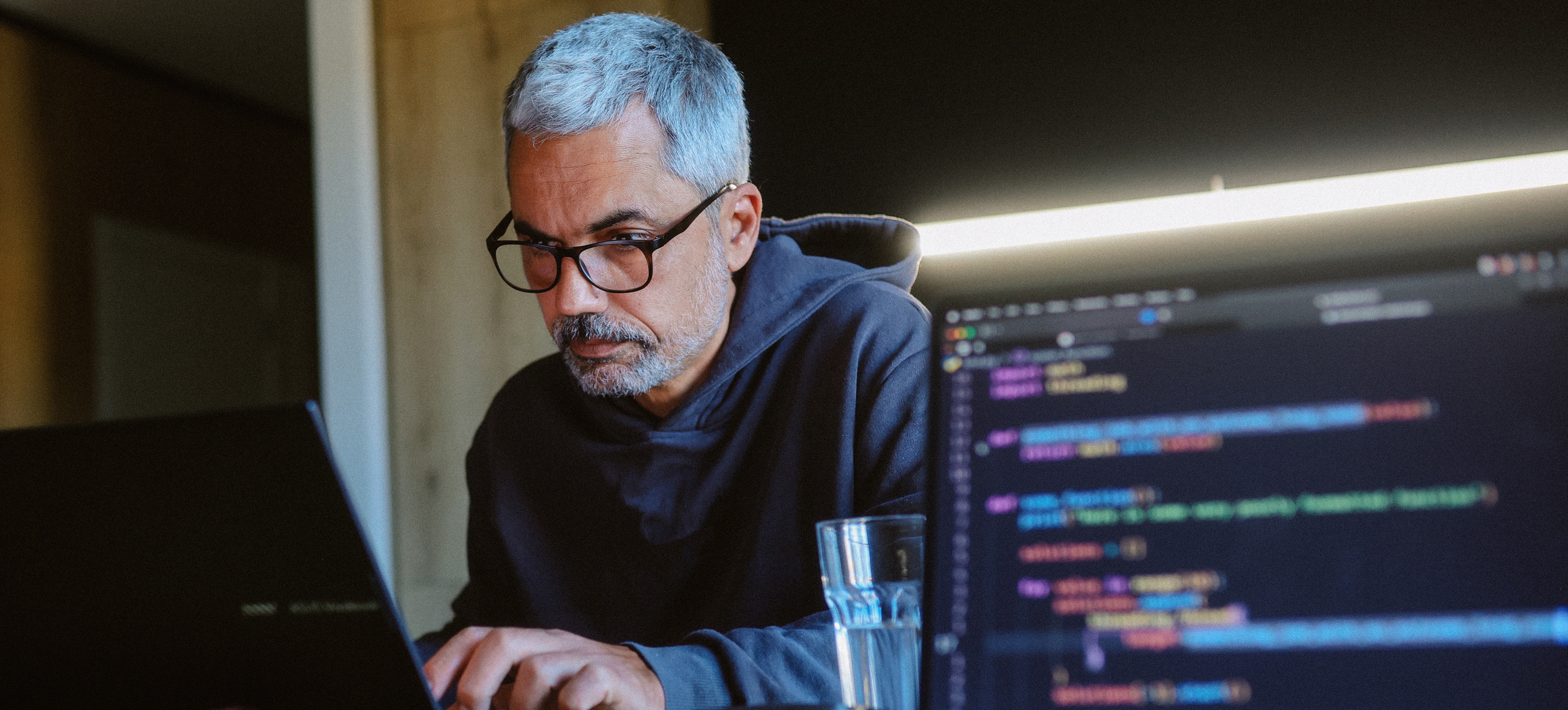 [Featured Image] A computer programmer on a computer working on a project using blockchain programming.