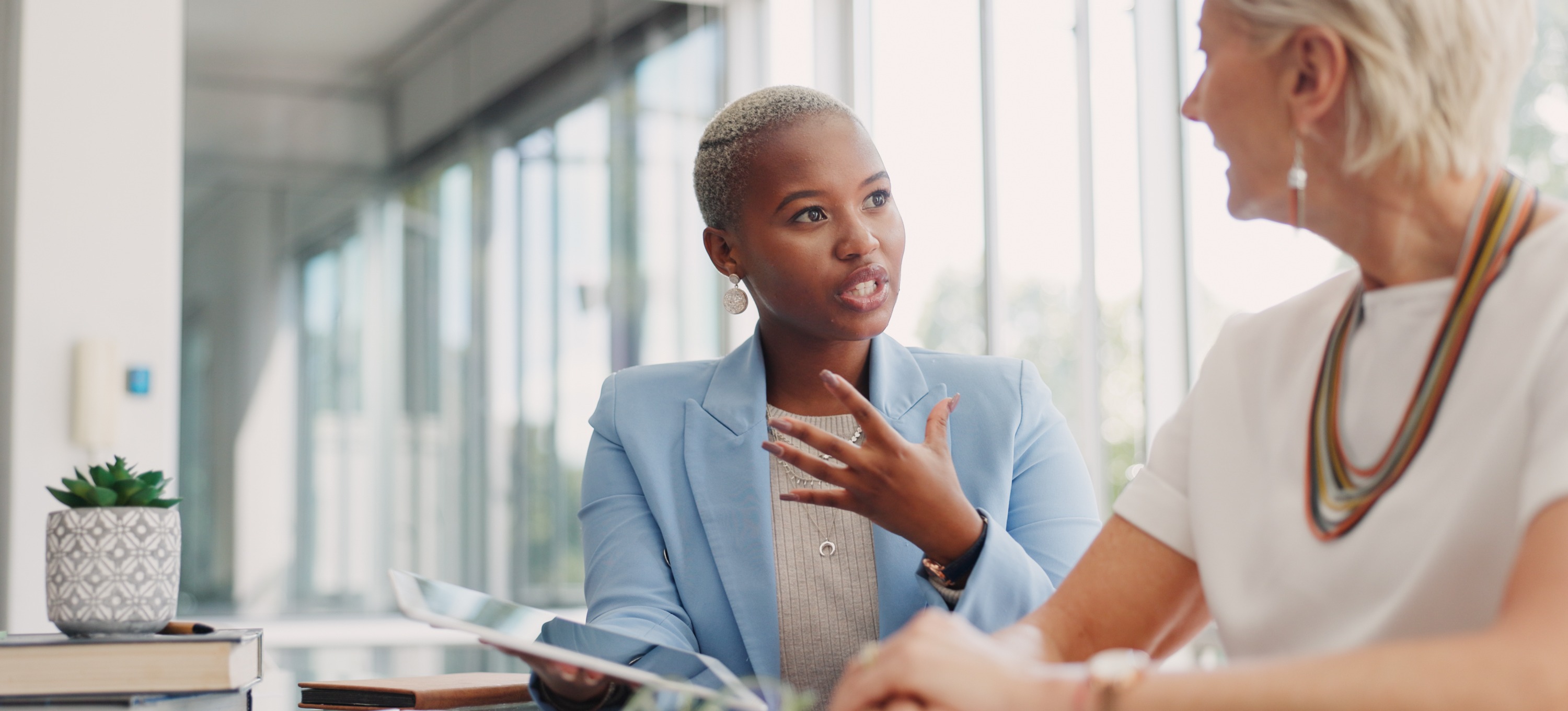 [Feature Image] A young business professional meets with their mentor to ask the question, “Why get an MBA?” and plan their learning journey to advance their career. 
