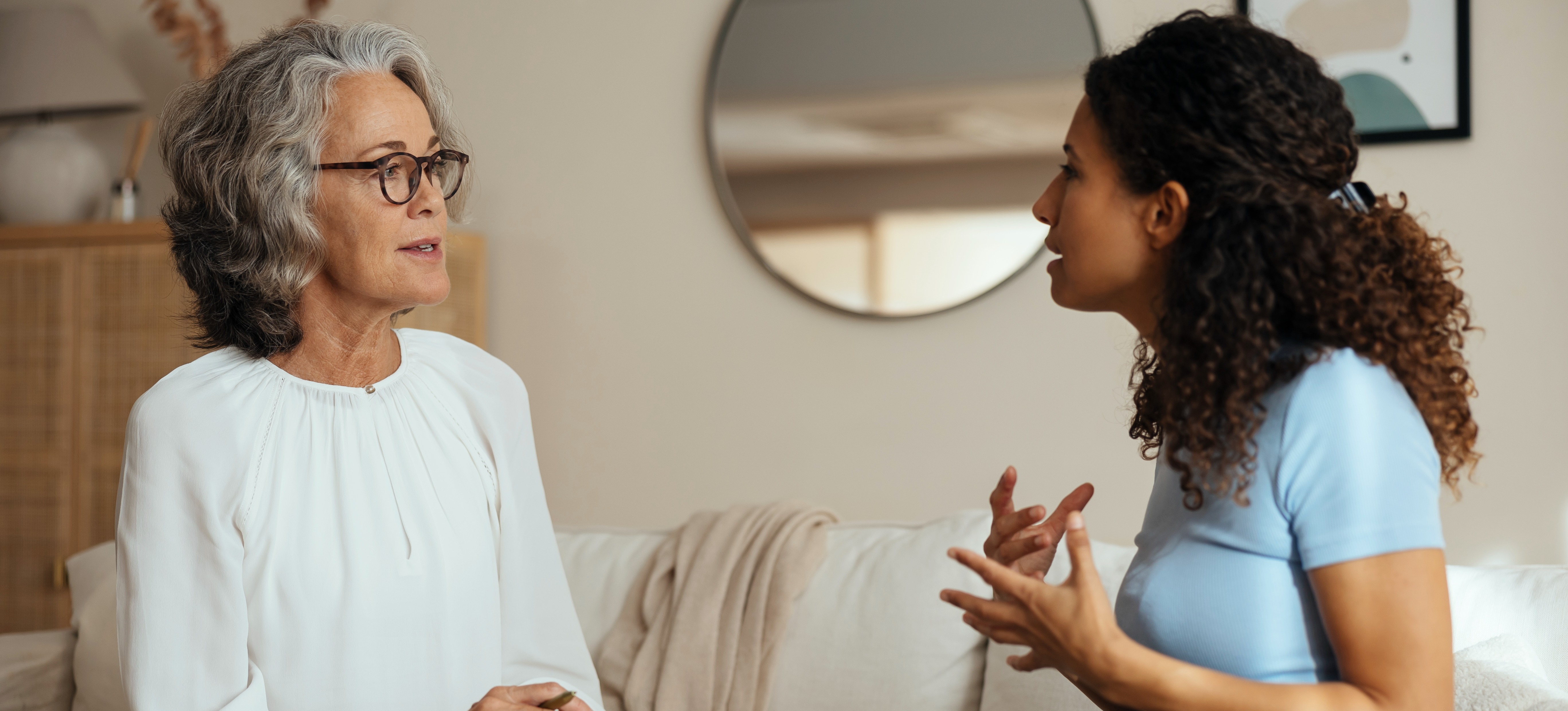 [Featured Image] A psychiatrist, one of the highest paying psychology jobs, sits on a sofa and take notes while listening to a patient. 
