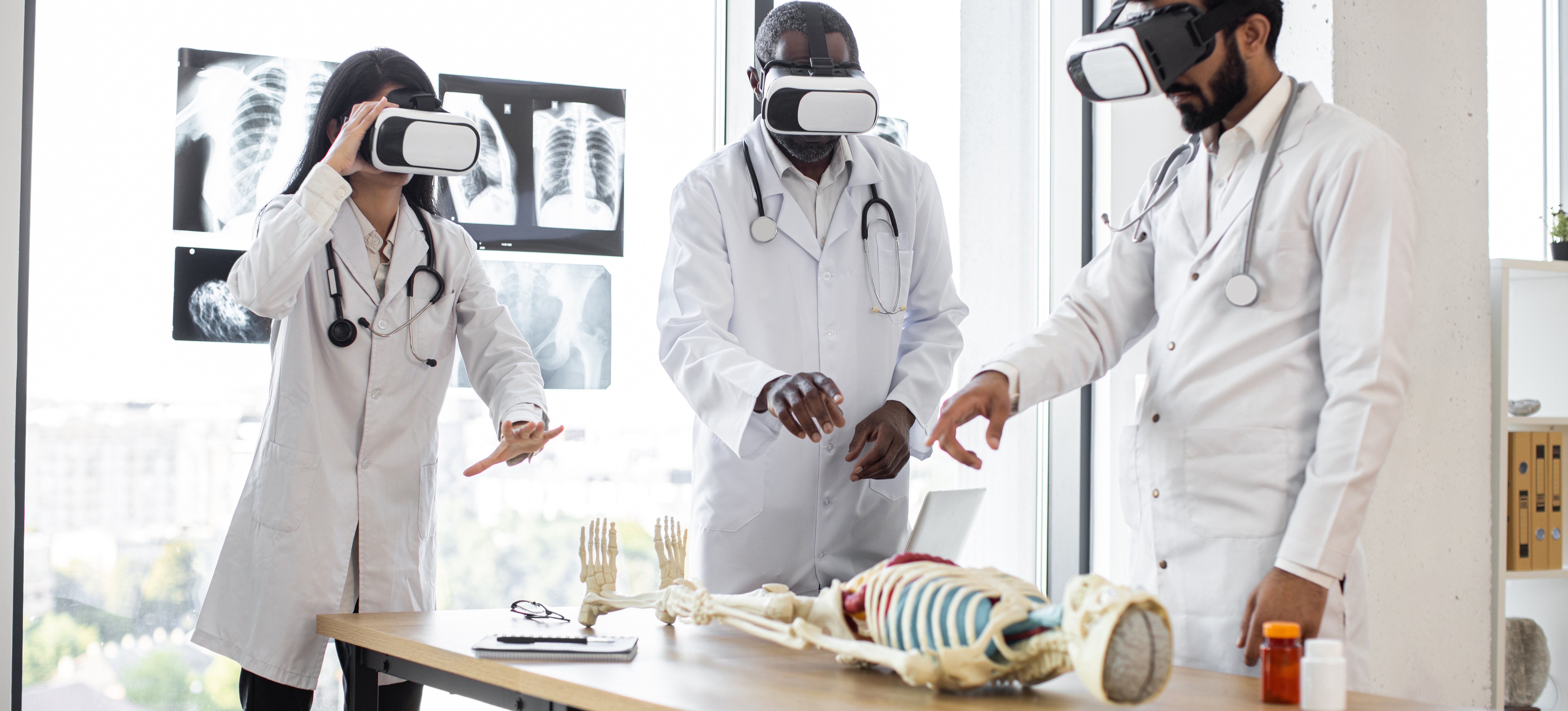[Hauptbild] Eine Gruppe von Ärzten nutzt Mixed Reality, um das menschliche Skelettsystem mithilfe eines Skelettmodells und einer VR-Brille zu untersuchen.