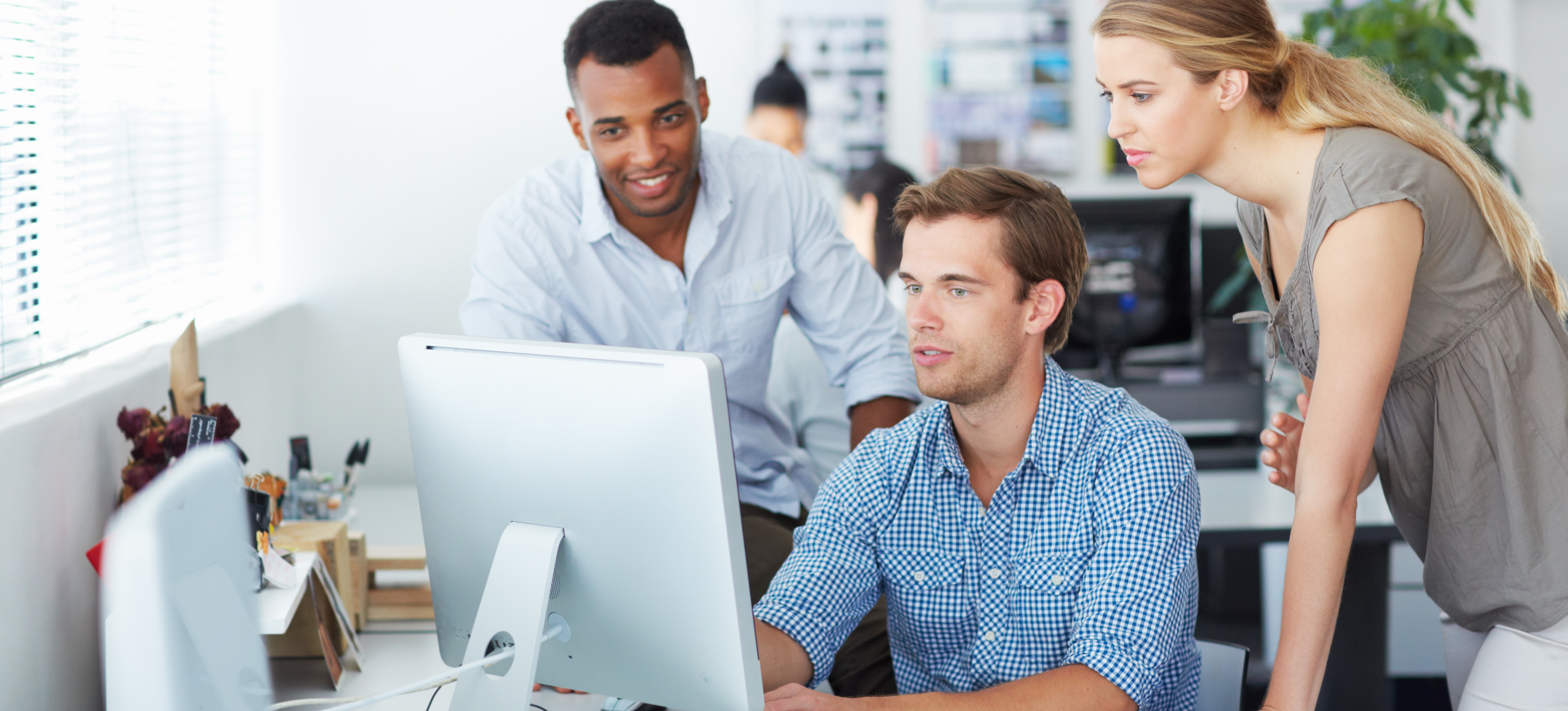 [Featured Image] Three machine learning professionals look at a computer screen in an office setting and discuss scaling laws for neural language models.
