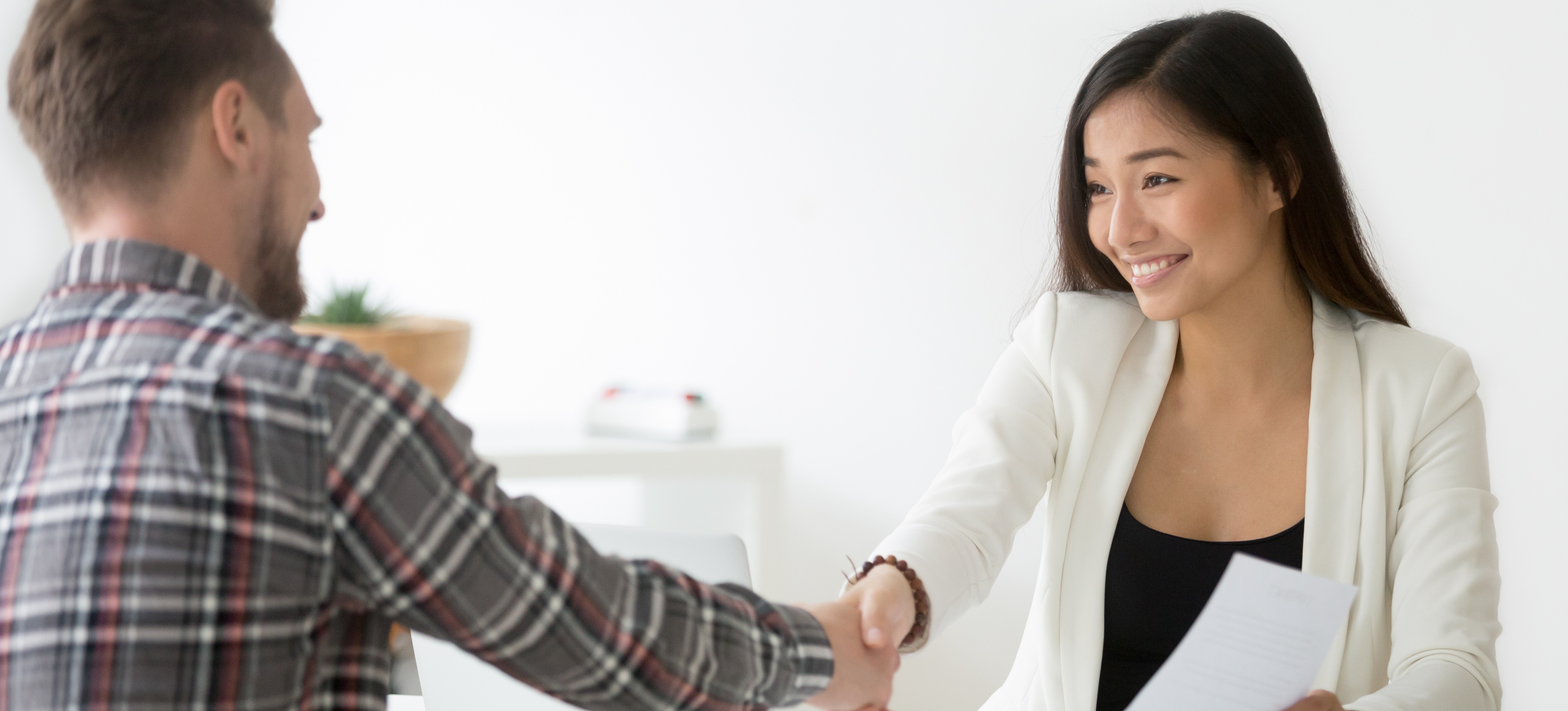 [Featured Image] An IT support specialist shakes hands with a potential employer during a job interview. 
