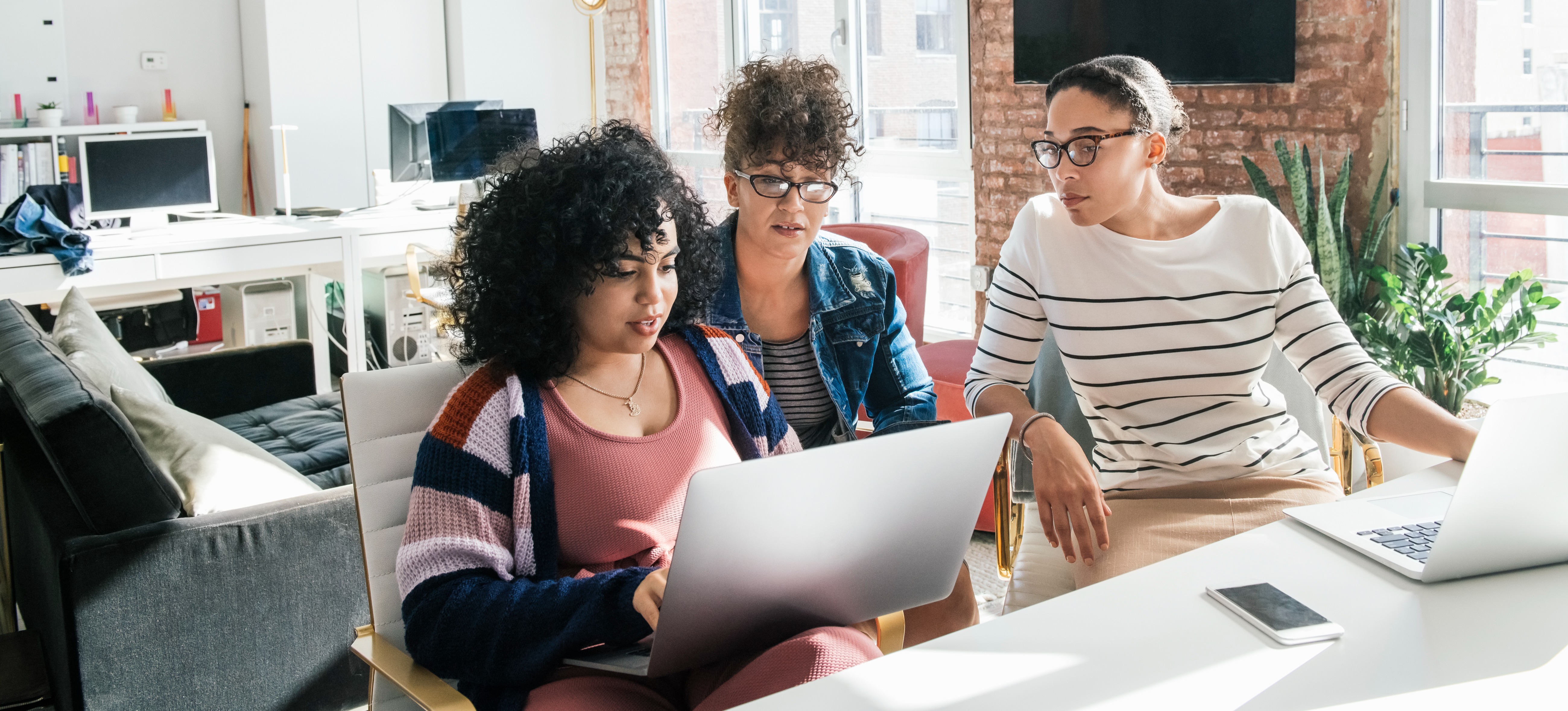 [Featured Image] Three women study information on a laptop computer. 