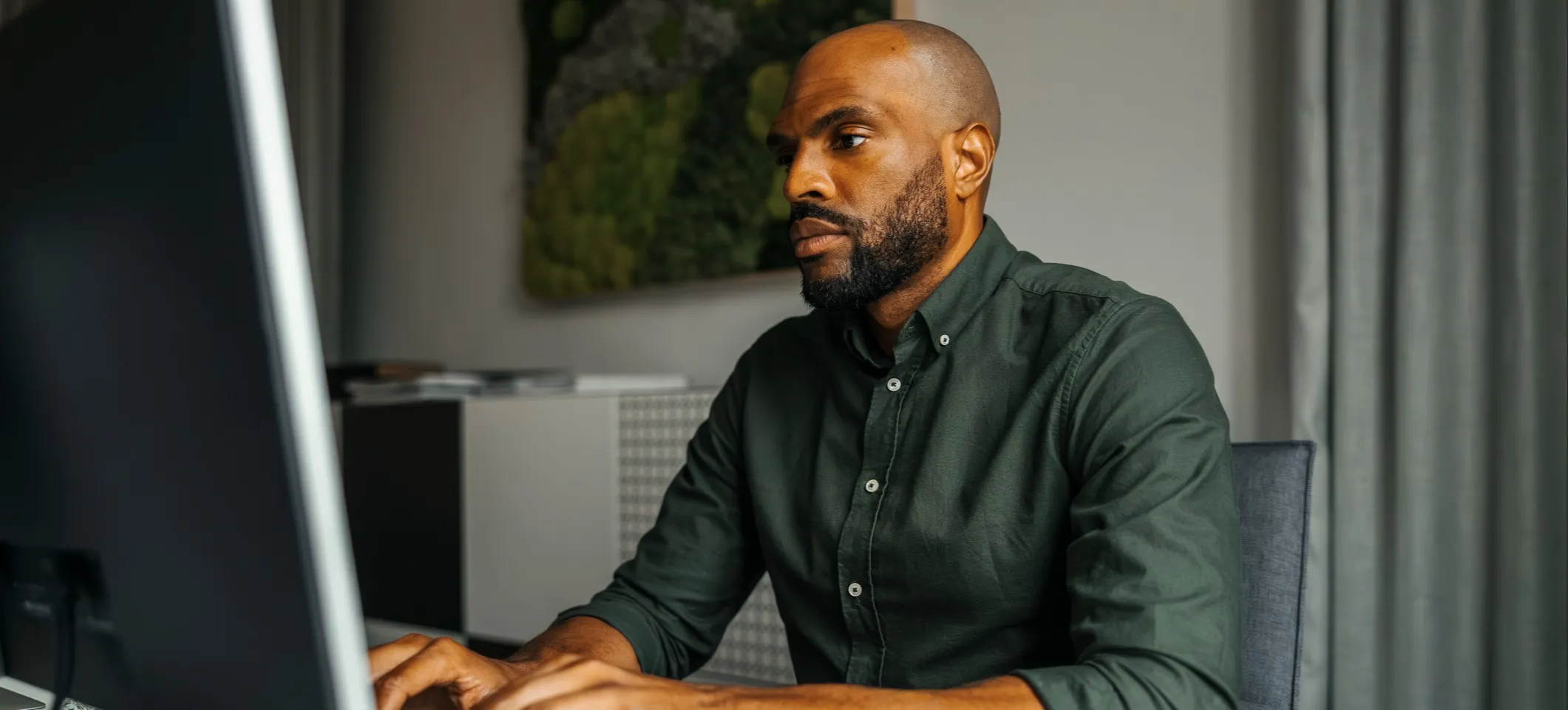 [Featured Image] An ethical hacker looks at their computer screen intently as they work to counter cybercrime. 
