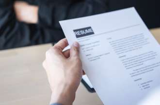 [Featured Images] A photograph of a resume in the hands of a job applicant.