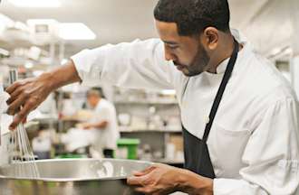 [Featured Image] A head chef combines food in a commercial kitchen after learning about California jobs in demand and applying their training and passion for culinary arts.  
