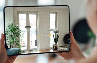 [Featured image] A woman uses an augmented reality app on a tablet to measure space for her interior design career. 
