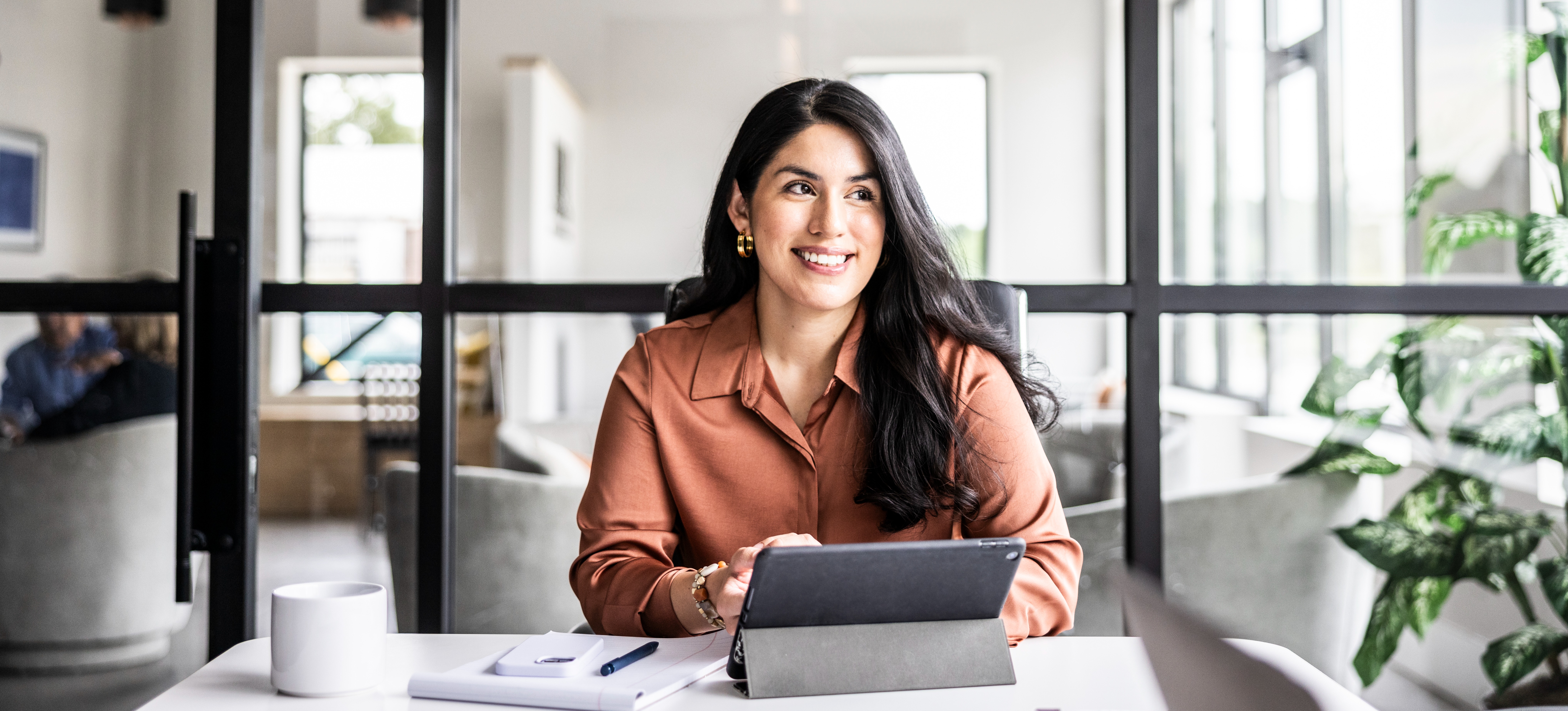 [Feature Image] A job seeker smiles and looks away from their laptop after searching for and finding some potentially high-paying entry-level management jobs.
