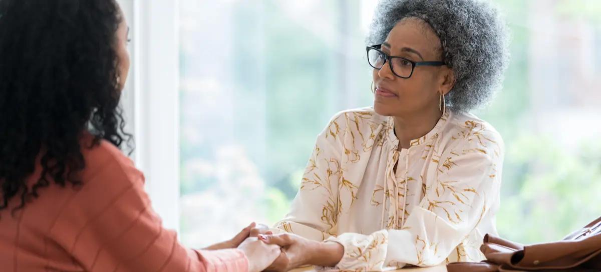 [Featured Image] Two friends sitting across the table have an emotional conversation and support each other, effectively answering the question, “Why is empathy important?”