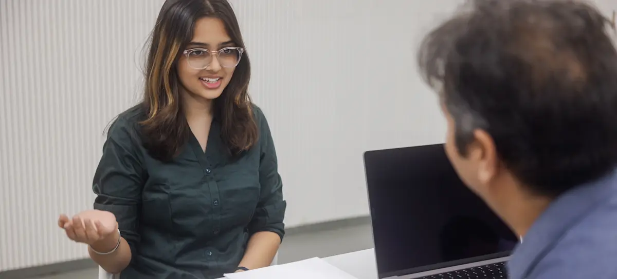 [Featured Image]: A person confidently speaks with a recruiter after preparing from a list of UX designer interview questions and answers.