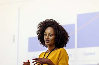 [Featured Image]: The marketing manager, wearing a yellow top, is making a PowerPoint presentation.