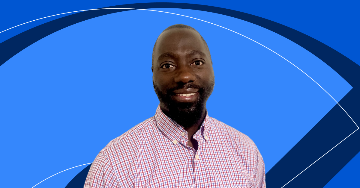 [Featured image] Learner Bonginkosi Biyela, who found Coursera Coach to be helpful, poses in front of a blue Coursera background. 