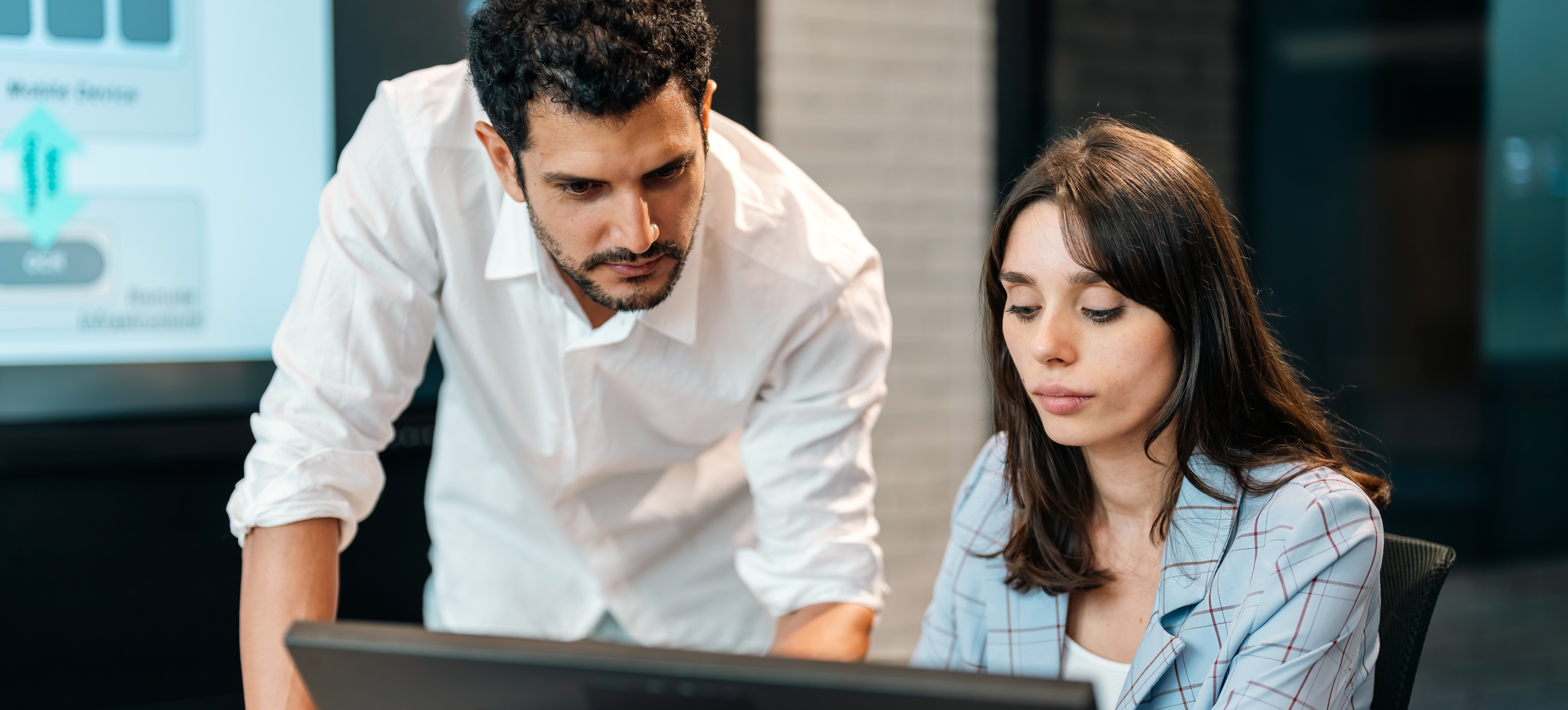 [Featured image] Two AI researchers in an office using text classification to organize text data on a computer.
