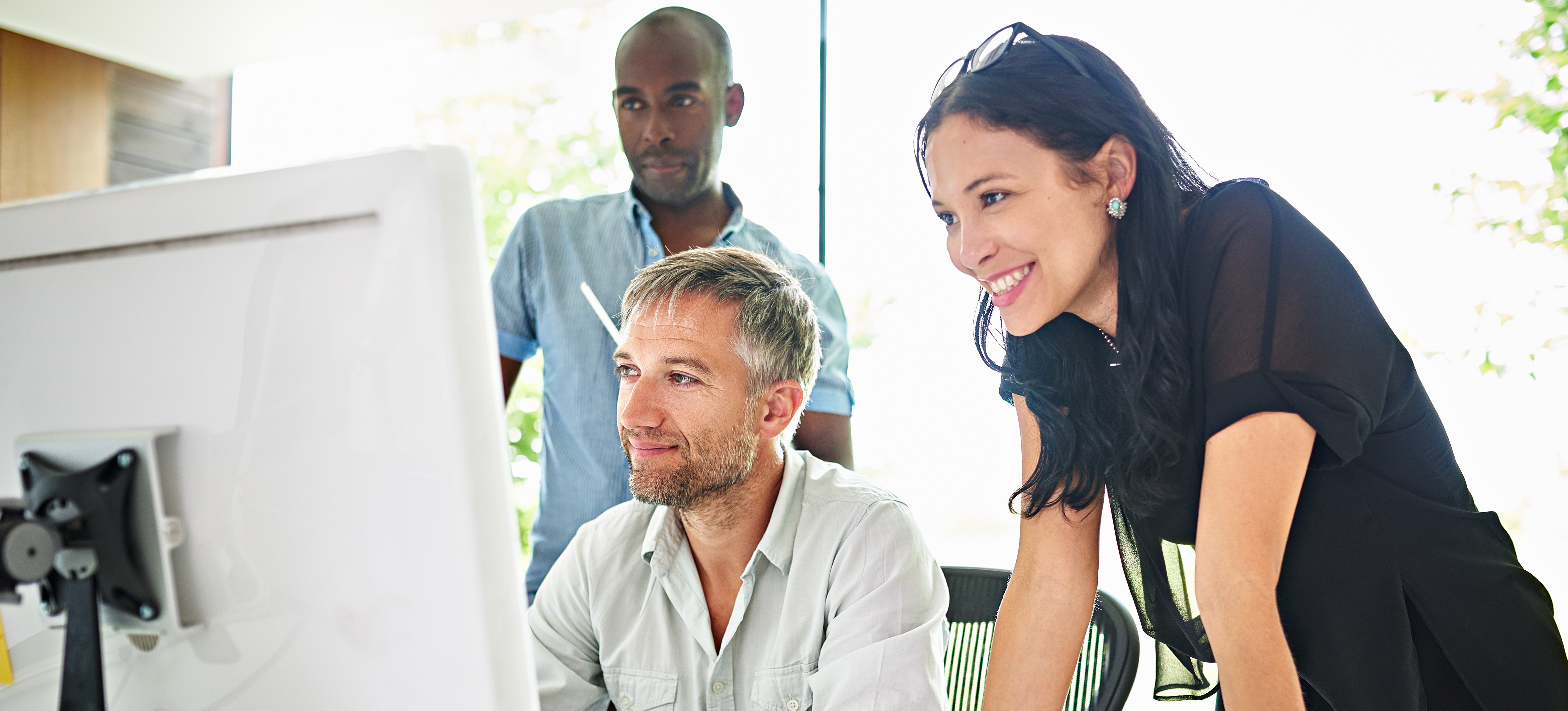 [Featured Image] A group of three machine learning engineers look at a computer screen on which they use an SVM to analyze data. 

