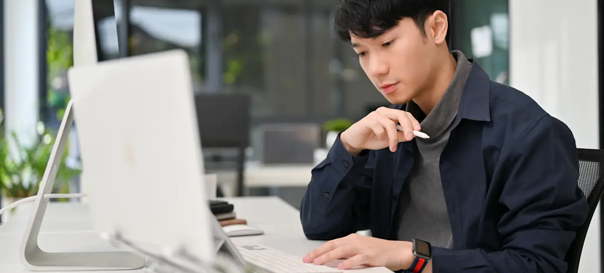 [Featured Image] A programmer is working on their laptop and a second computer monitor with design patterns in Python in an office setting.
