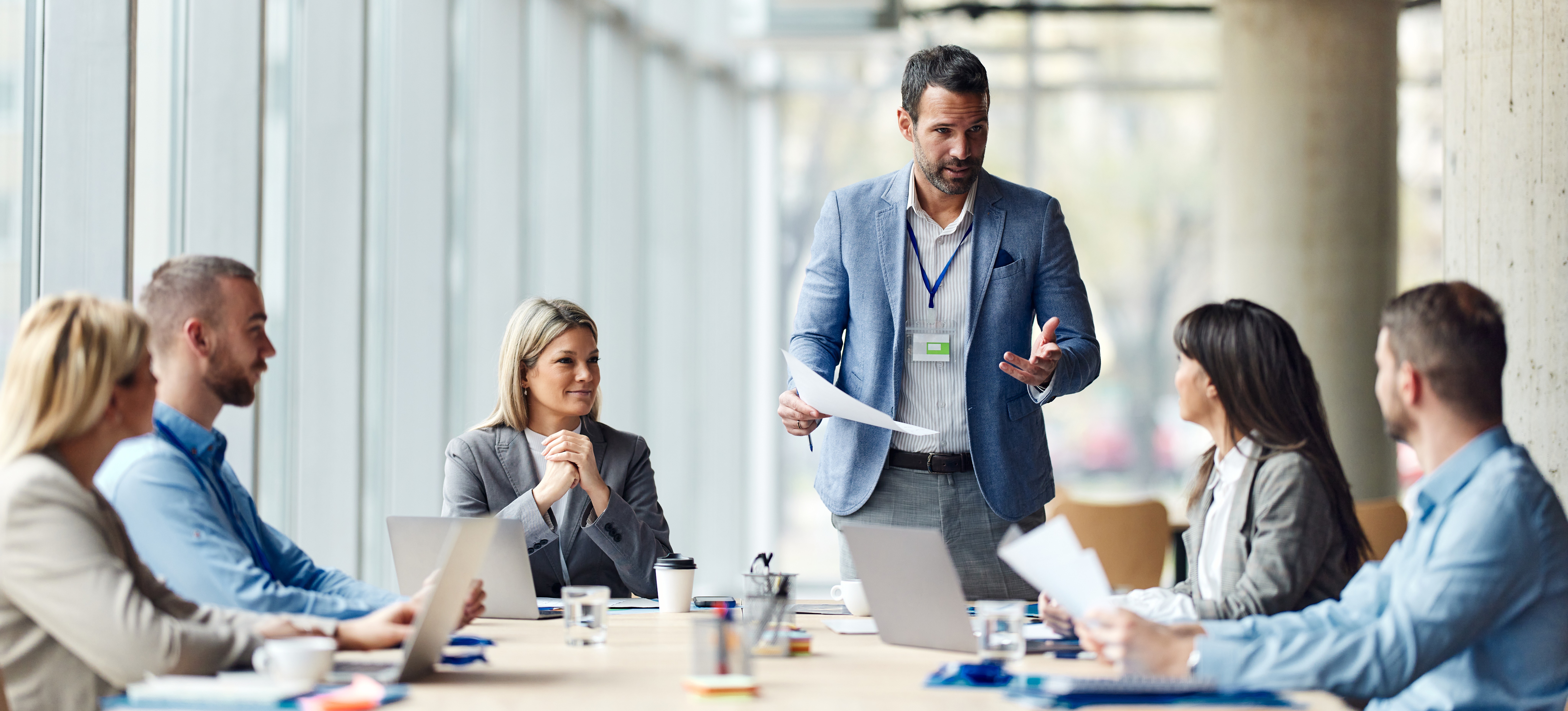 [Featured Image] A meeting led by a businessman who earned their business management certification is discussing the benefits of earning certificates. 
