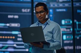 [Featured Image] An IT worker looks at his laptop, studying the differences between a hub vs switch.