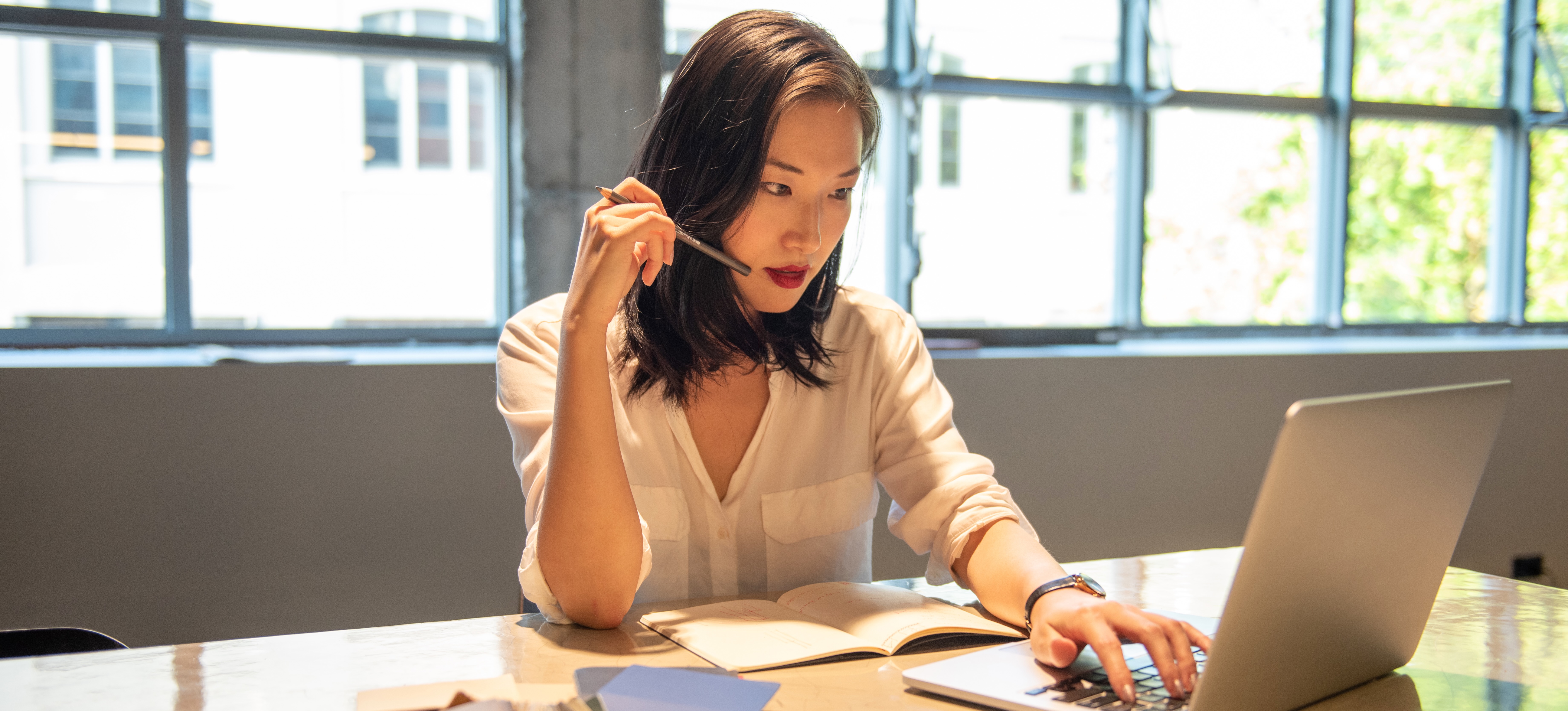 [Featured Image] A worker sits on their laptop and researches imposter syndrome and how to overcome it.