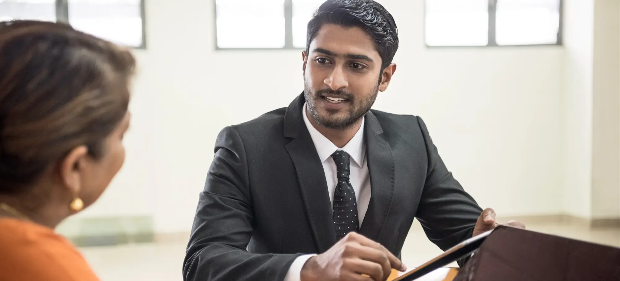 [Featured Image] An employer sits across a desk from a potential employee and asks machine learning interview questions.
