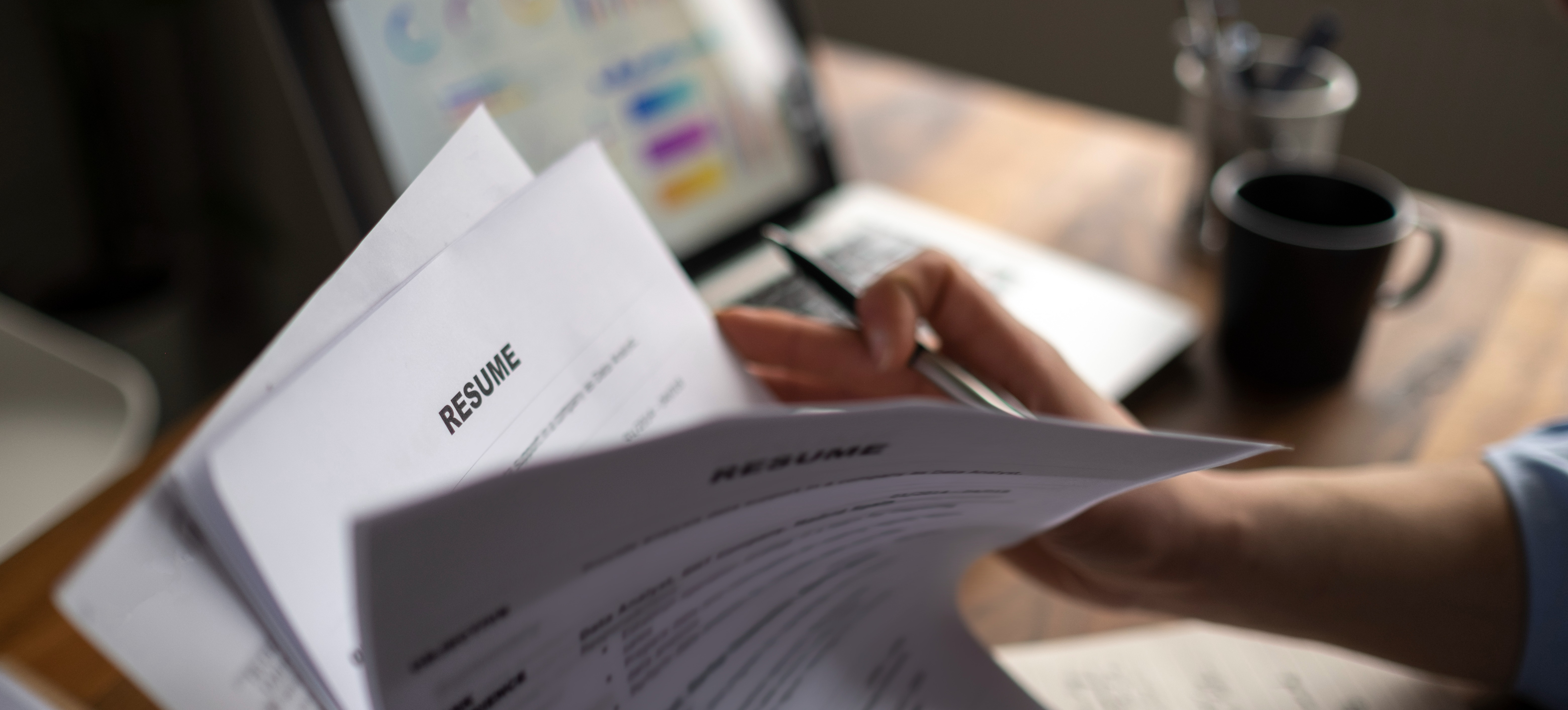 [Featured Image] A professional is reading through a stack of big data resumes.
