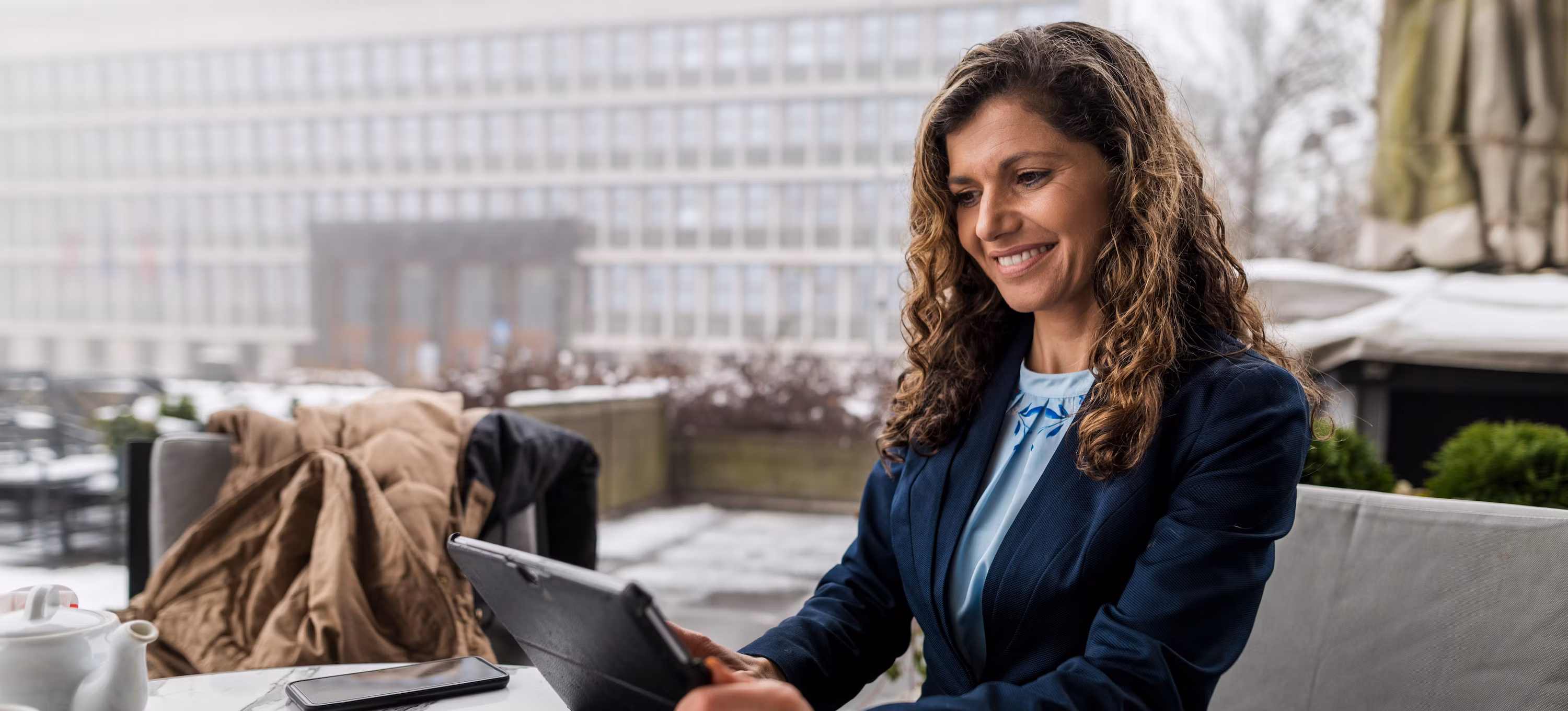 [Featured image] Woman wearing blue blouse holding a tablet.