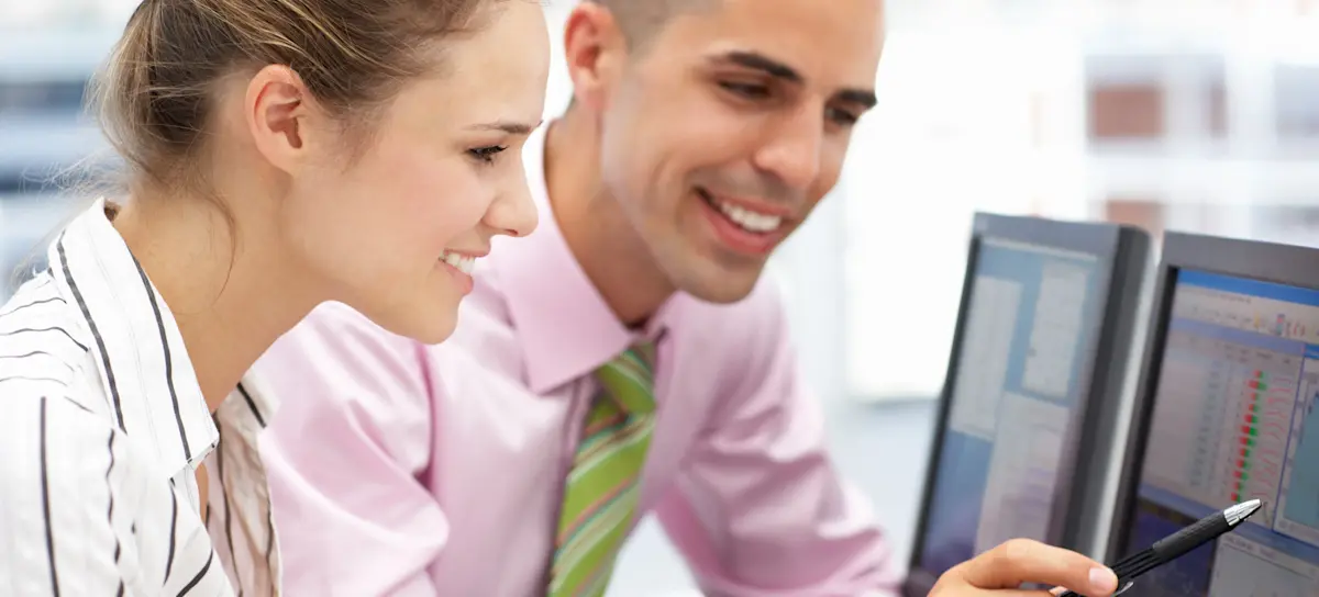 [Featured Image] A statistician points to data and a graph created with TensorFlow on their computer screen as another statistician looks on.
