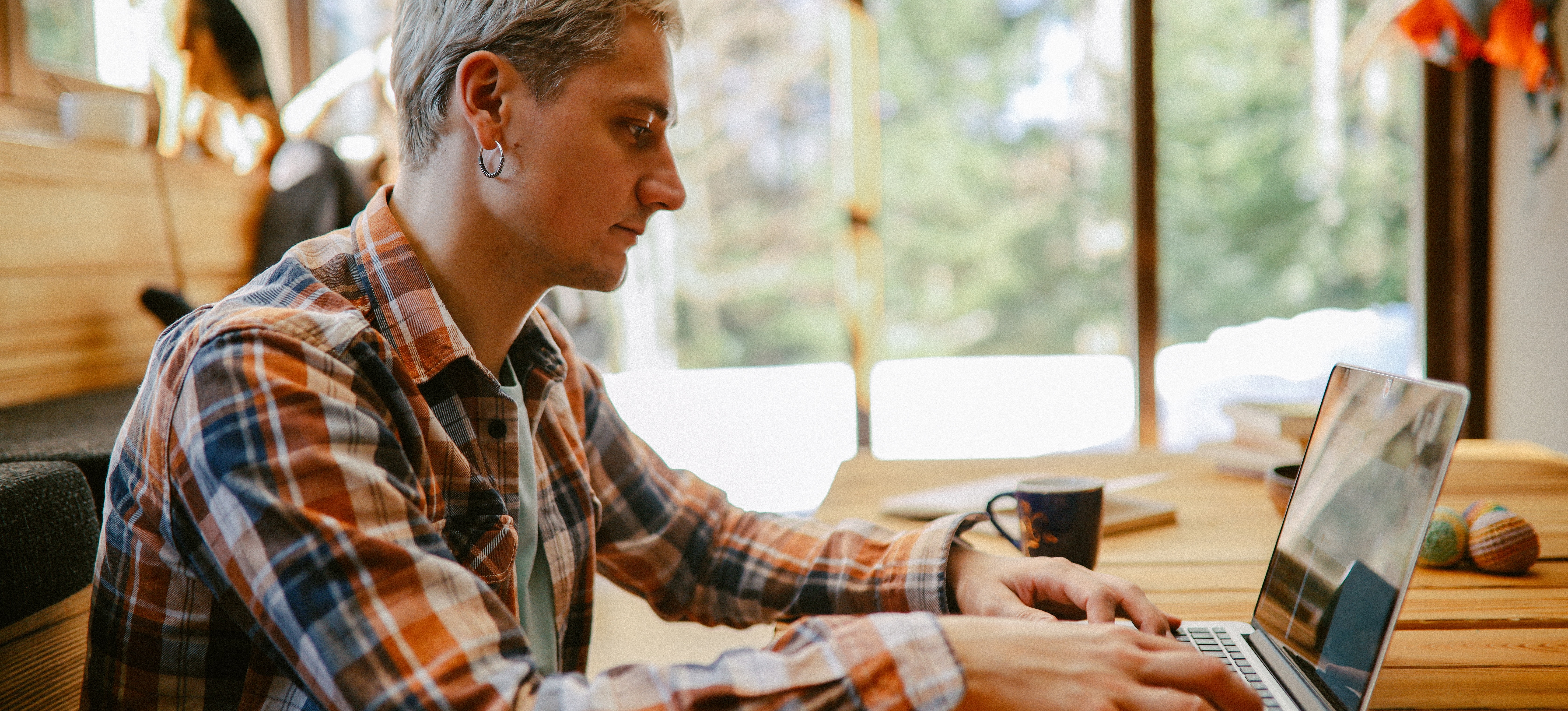 [Featured Image] A software developer sits at a table with a laptop and uses a procedural programming language. 