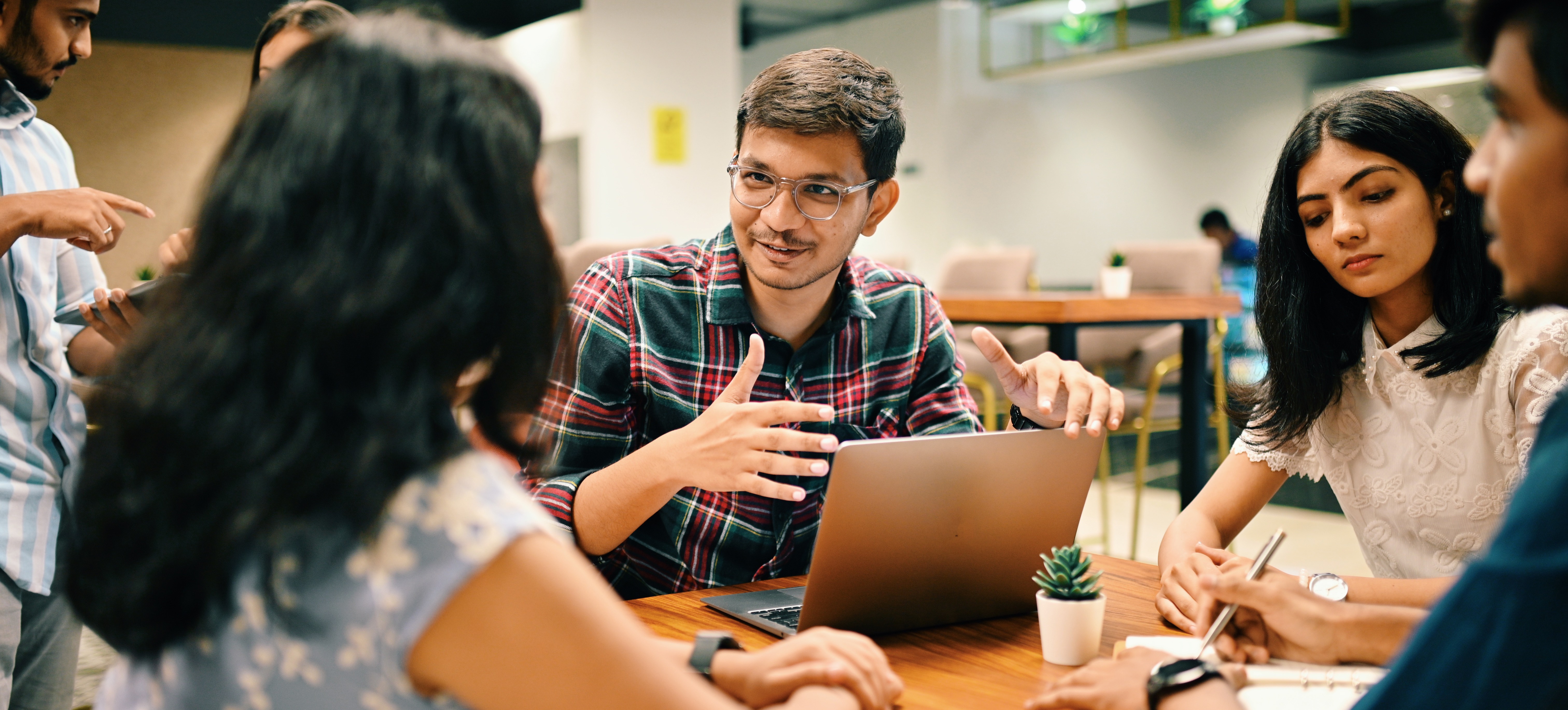 [Featured image] A group of employees for a tech company sit around a meeting table.