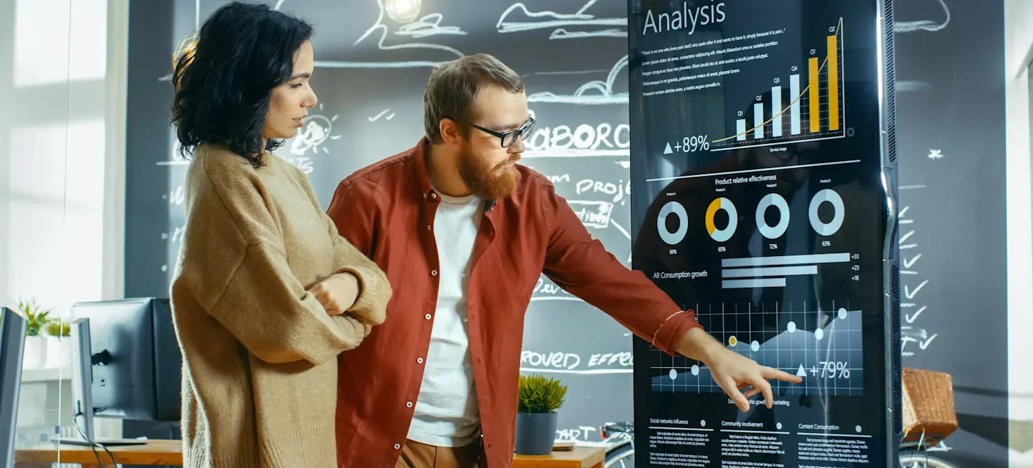 [Featured image] Two sales reps review analytics from their e-commerce platform.
