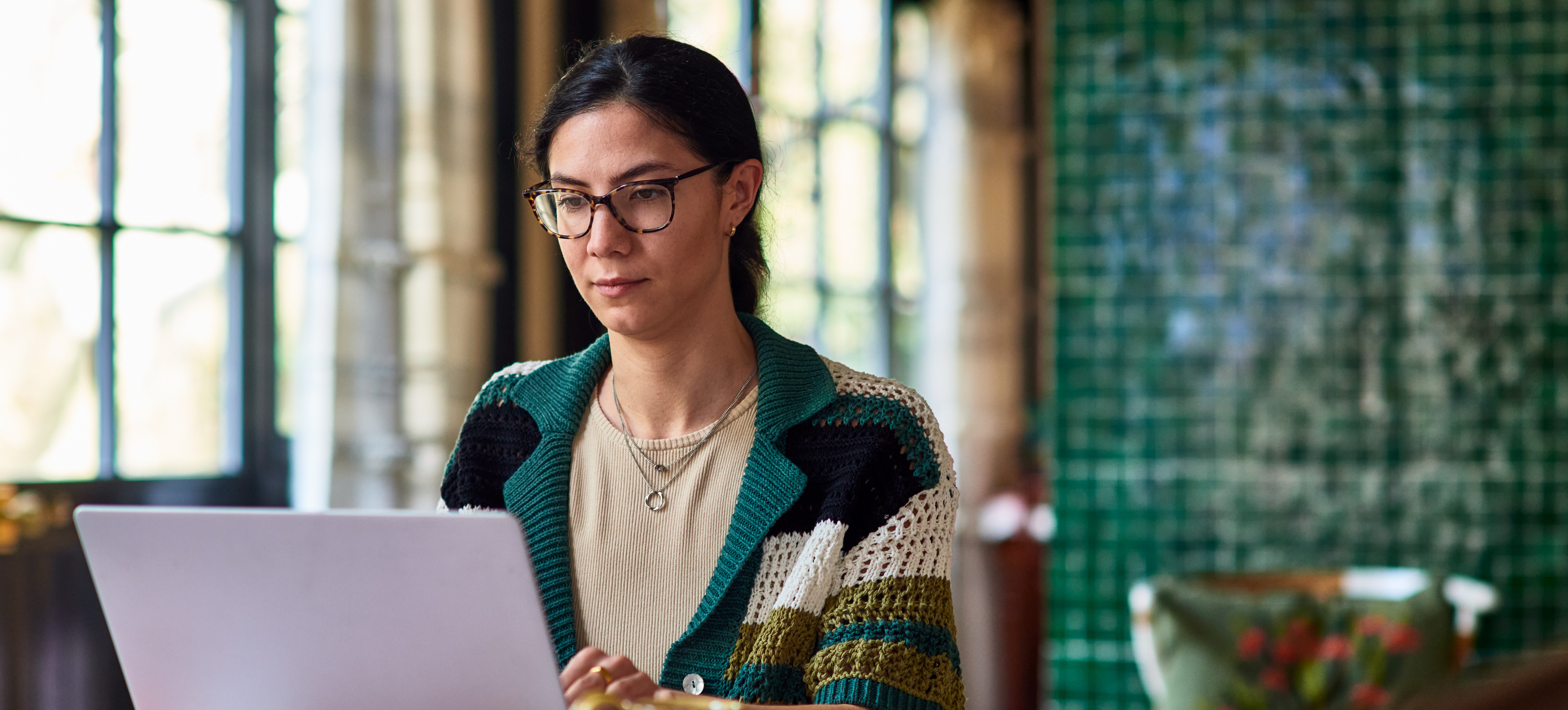 [Featured Image] A women is on her laptop learning how to lock cells in google sheets.