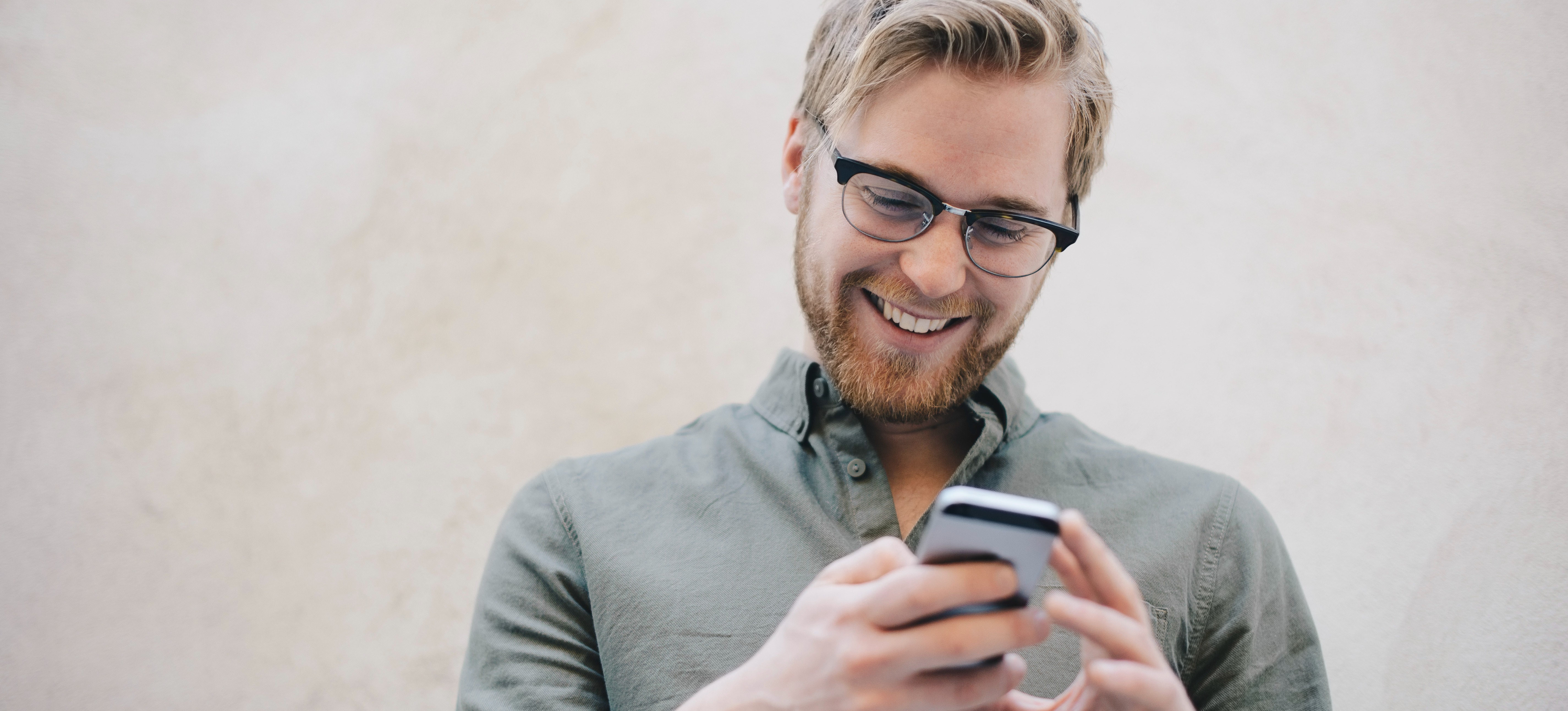 [Image en vedette] Un développeur Android souriant regarde son smartphone.
