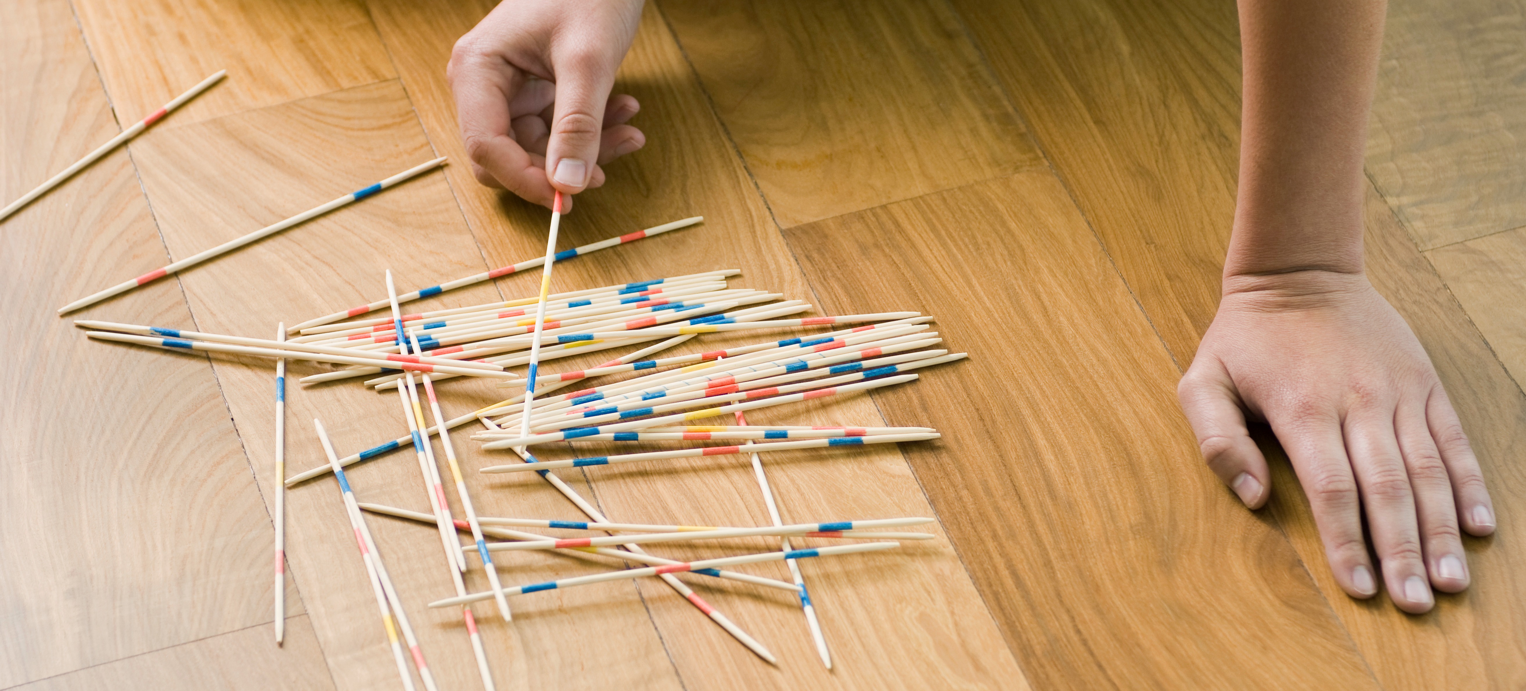 [Feature image] A person experiencing the nuances of correlation and causation through a game of Pickup Sticks.
